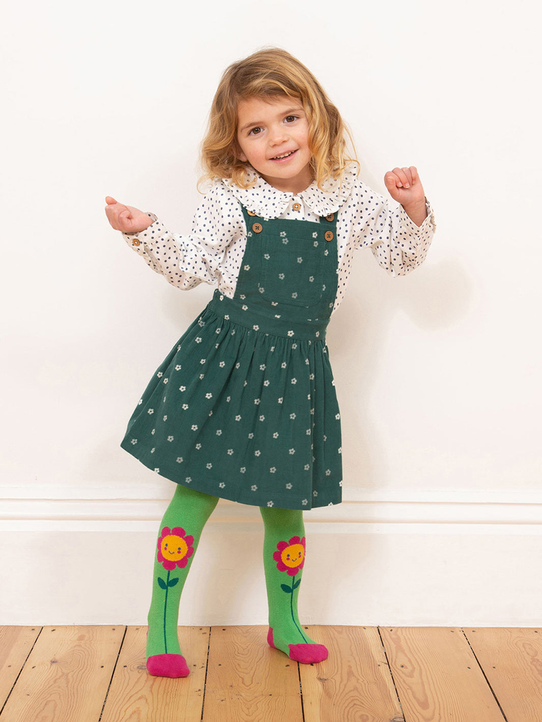 Niña usando la Blusa Dolly de algodón orgánico con estampado de lunares azul marino y cuello tipo muñeca.