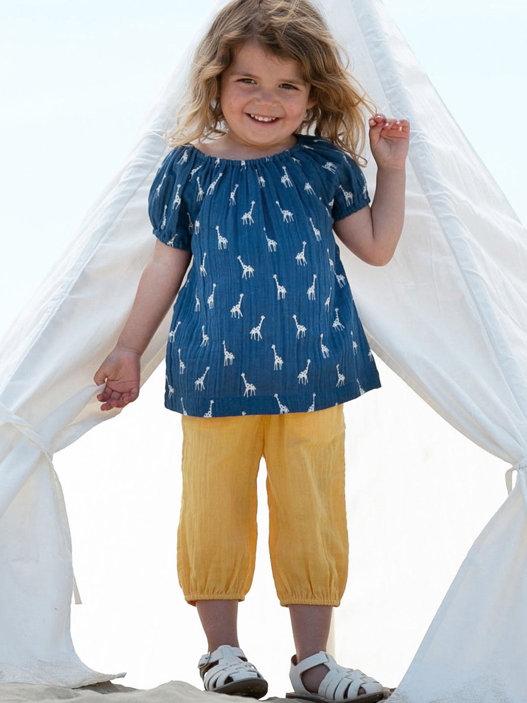 Niña disfrutando de la Blusa Lunares de Jirafitas de algodón orgánico, perfecta para la comodidad y el estilo en días cálidos.