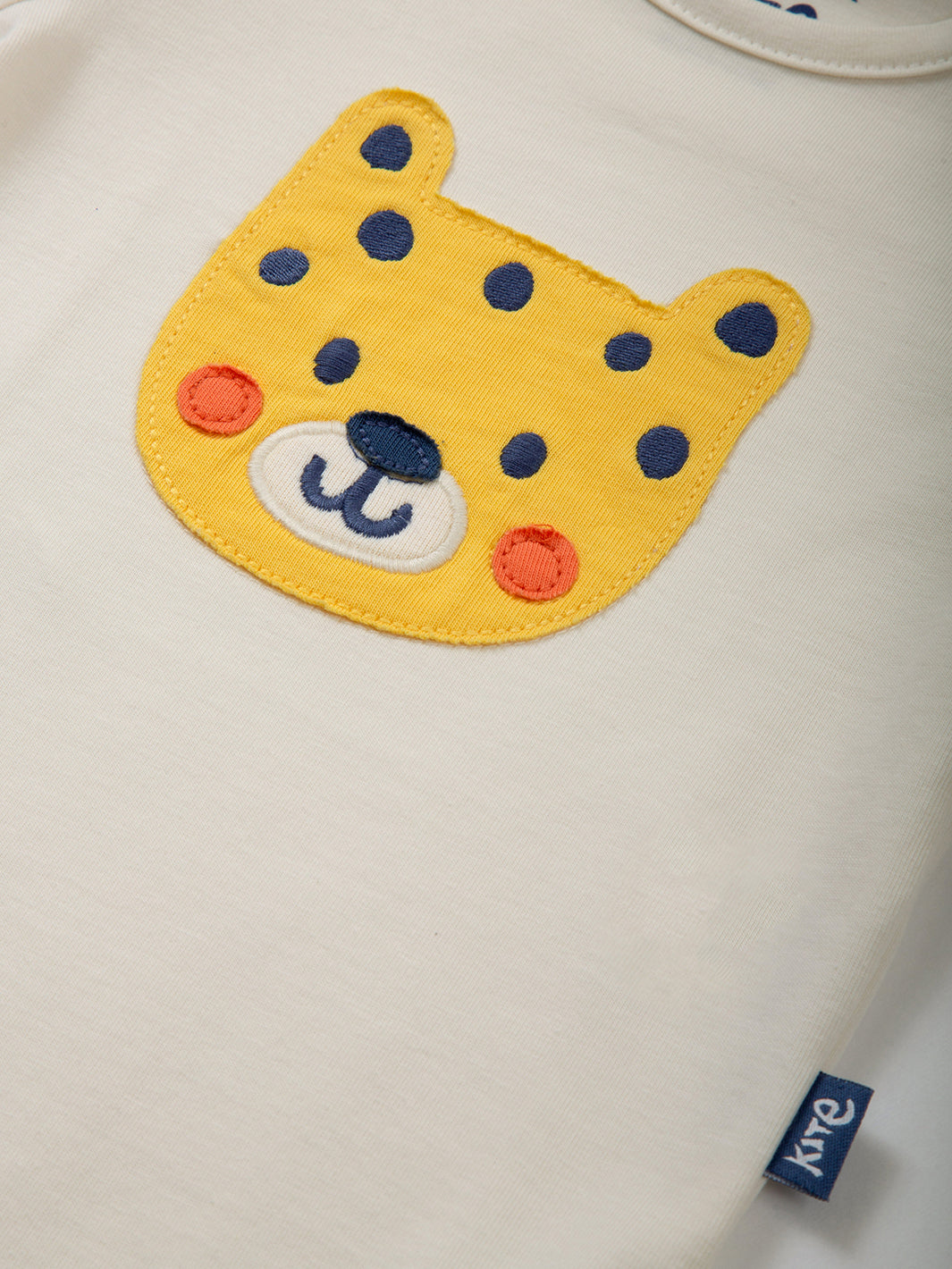 Detalle del apliqué de leopardo en el Body Hola Cachorro, algodón orgánico certificado GOTS.