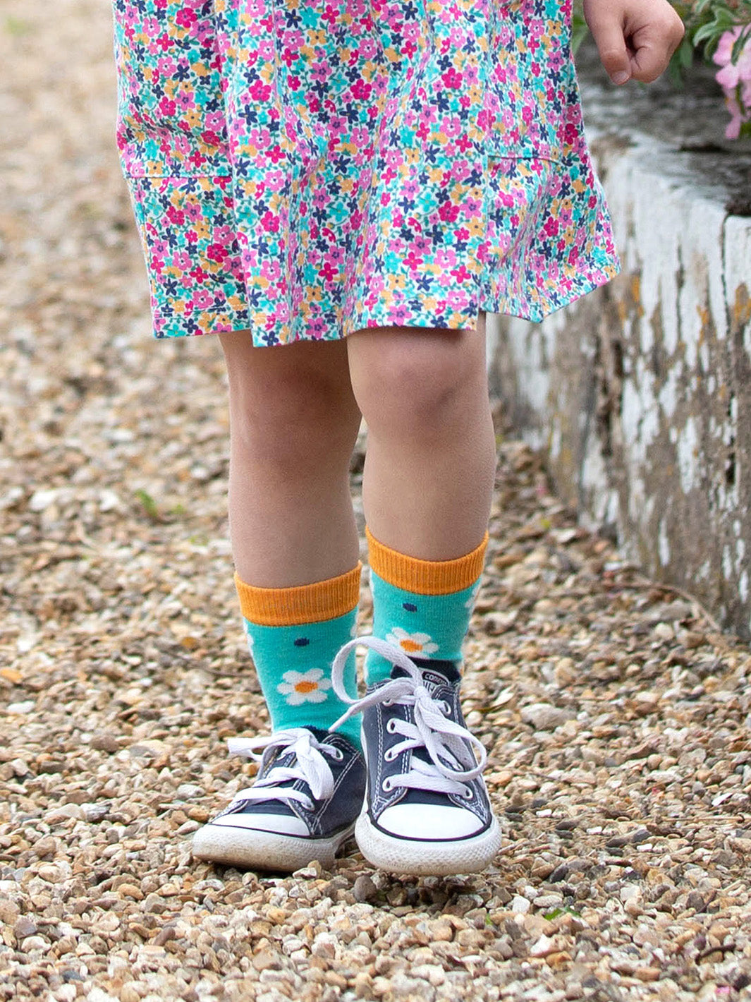 Niña usando calcetines de algodón orgánico con diseño de margaritas, ideales para el día a día.