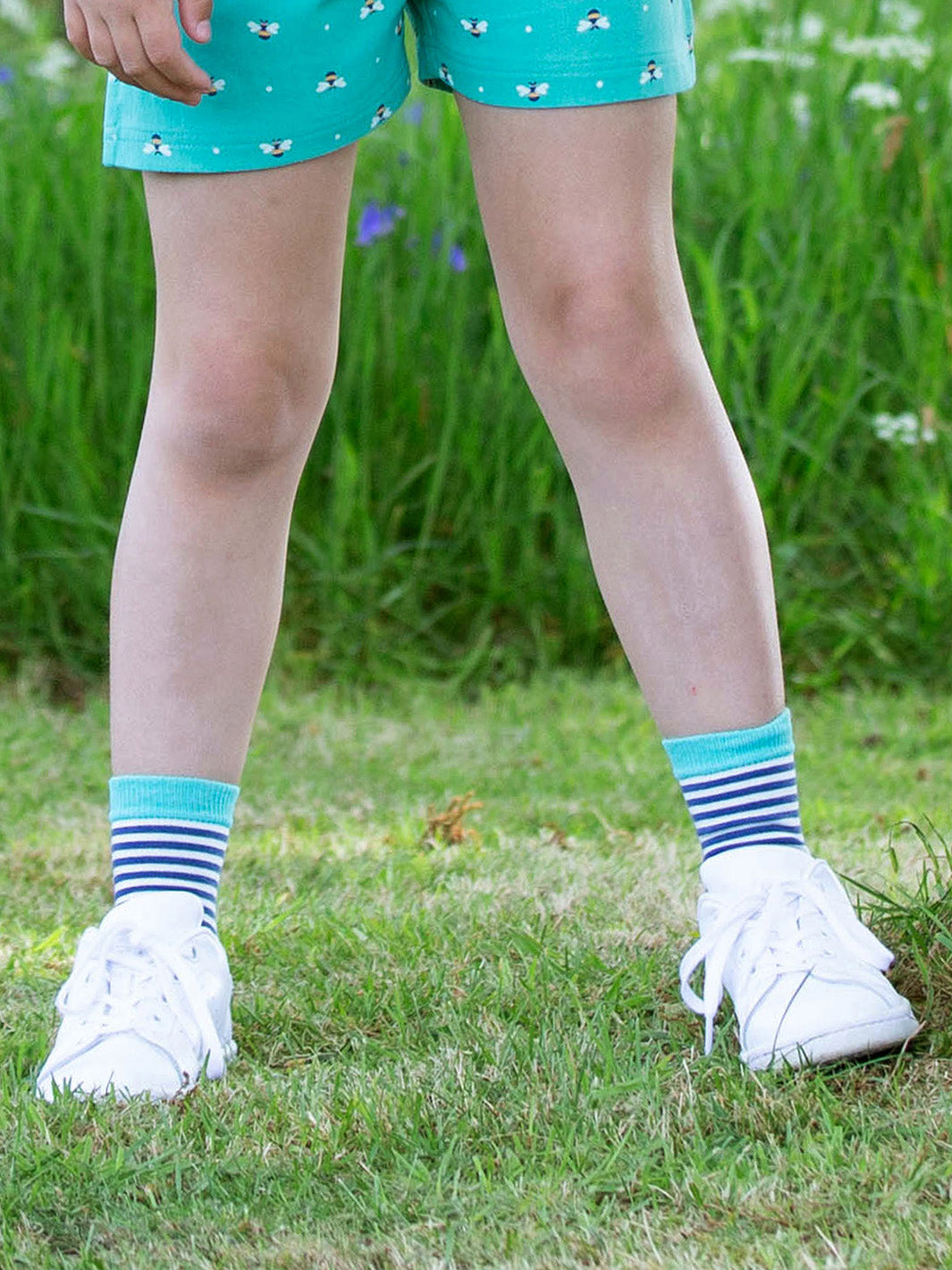 Niña usando calcetines de algodón orgánico con diseño de abeja reina, ideales para el día a día.