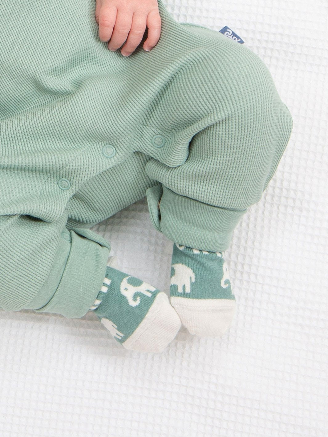 Pies de bebé calentitos con suaves calcetines de algodón orgánico en verde abeto, decorados con un adorable diseño de elefante, ideales para cualquier ocasión.