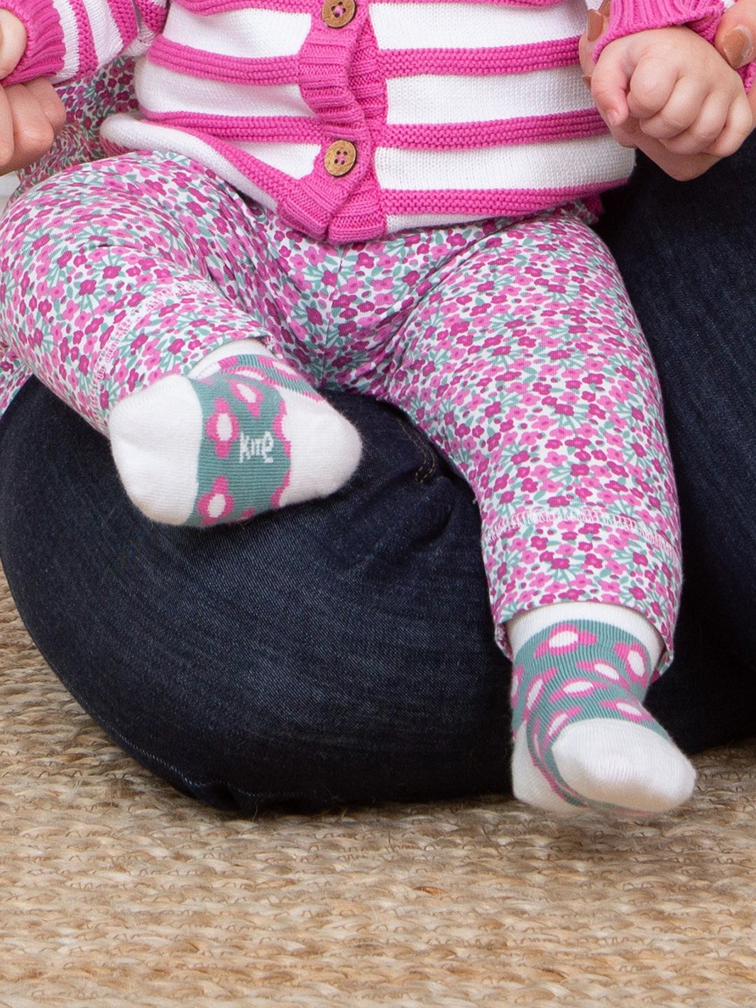 Pies de bebé abrigados con suaves calcetines de algodón orgánico en verde abeto, decorados con un delicado estampado floral, perfectos para complementar cualquier atuendo.