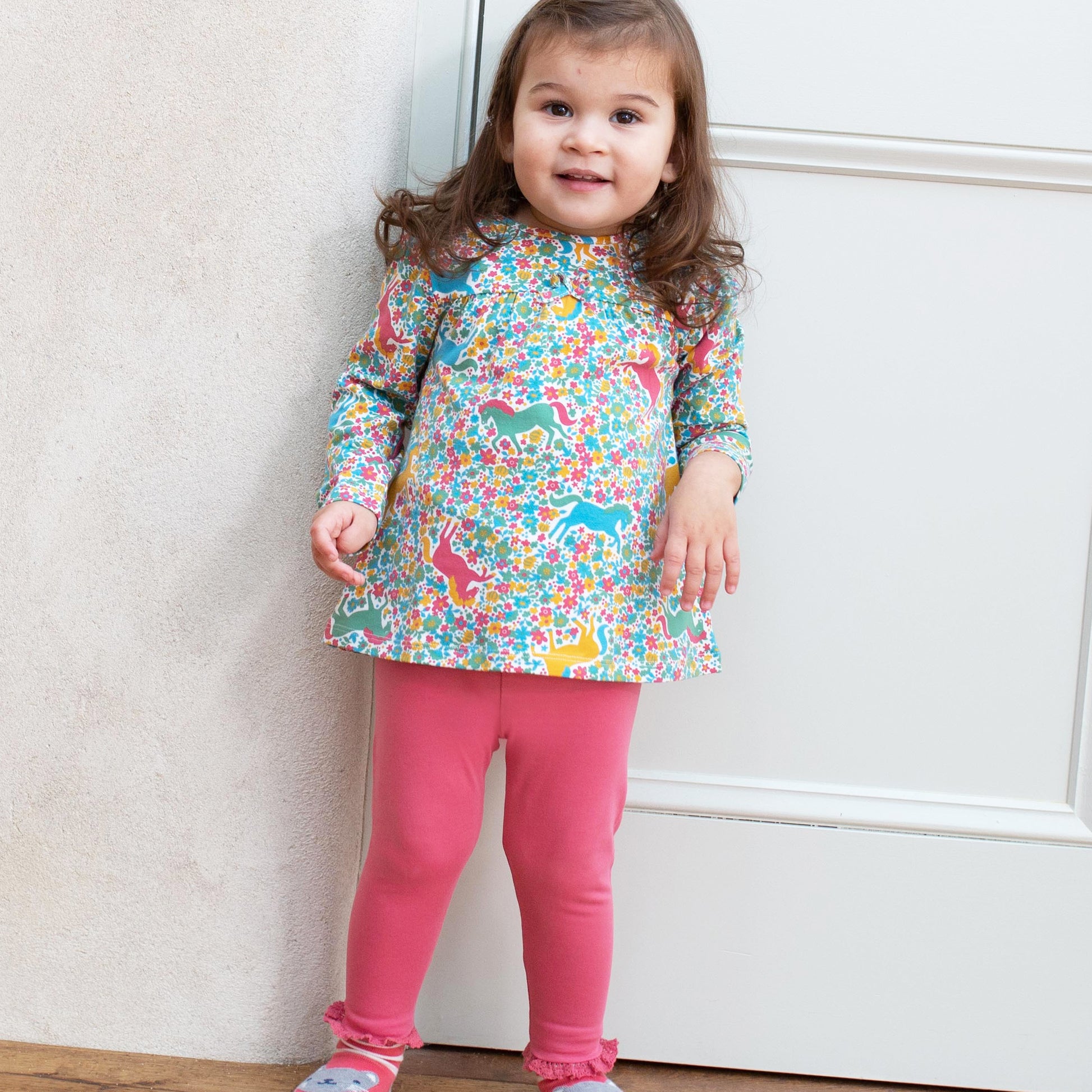 Niña usando las Calzas con Volantes de algodón orgánico, combinadas con una polera para un look adorable y cómodo.