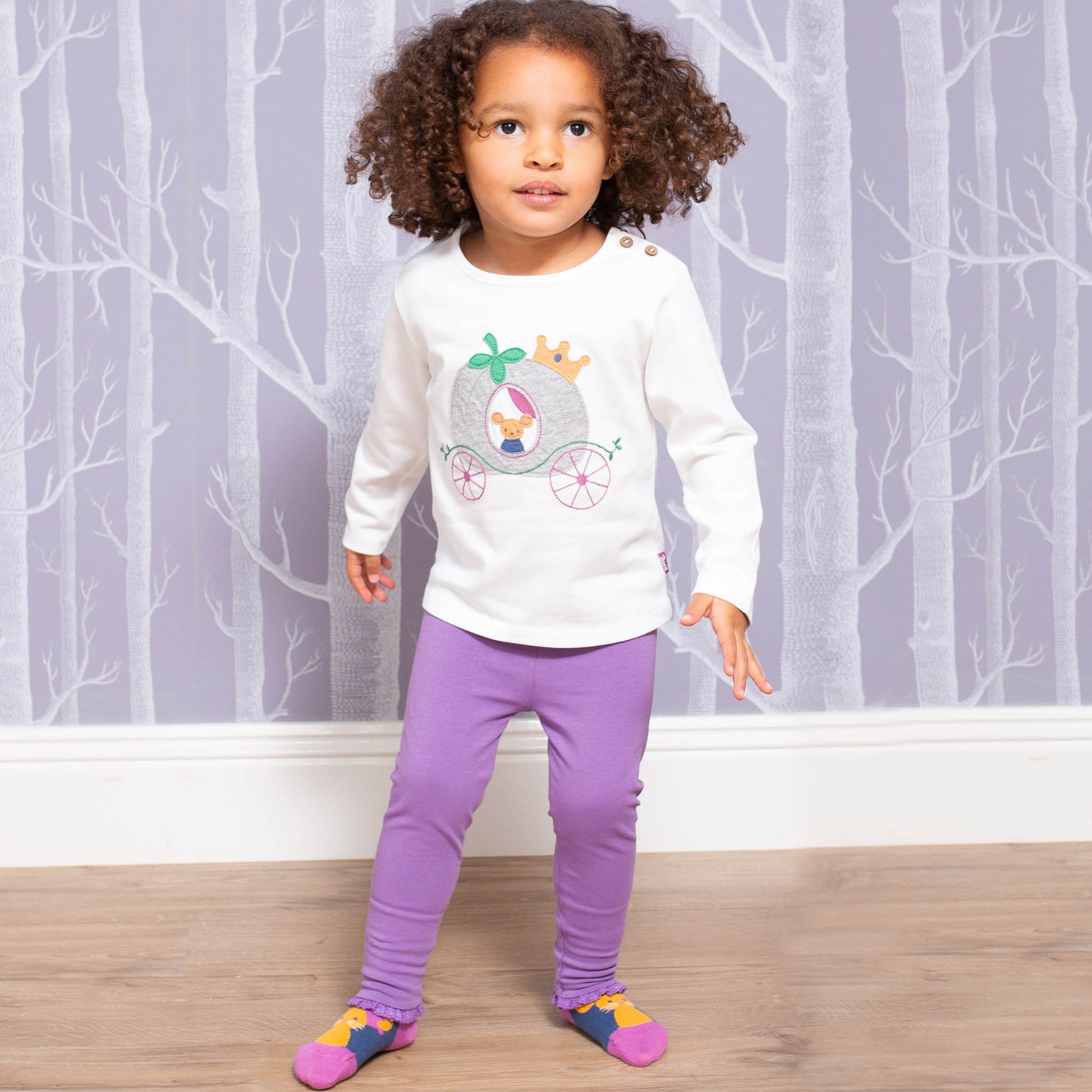 Niña usando las Calzas con Volantes de algodón orgánico, combinadas con una polera para un look adorable y cómodo.