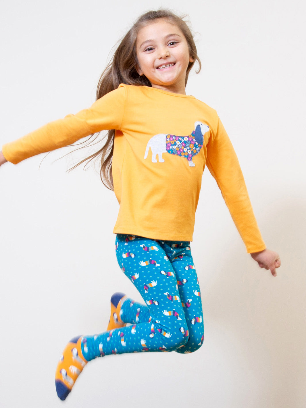 Niña vistiendo las Calzas Print de algodón orgánico con estampado de perros salchicha, look cómodo y lleno de diversión para el día a día.
