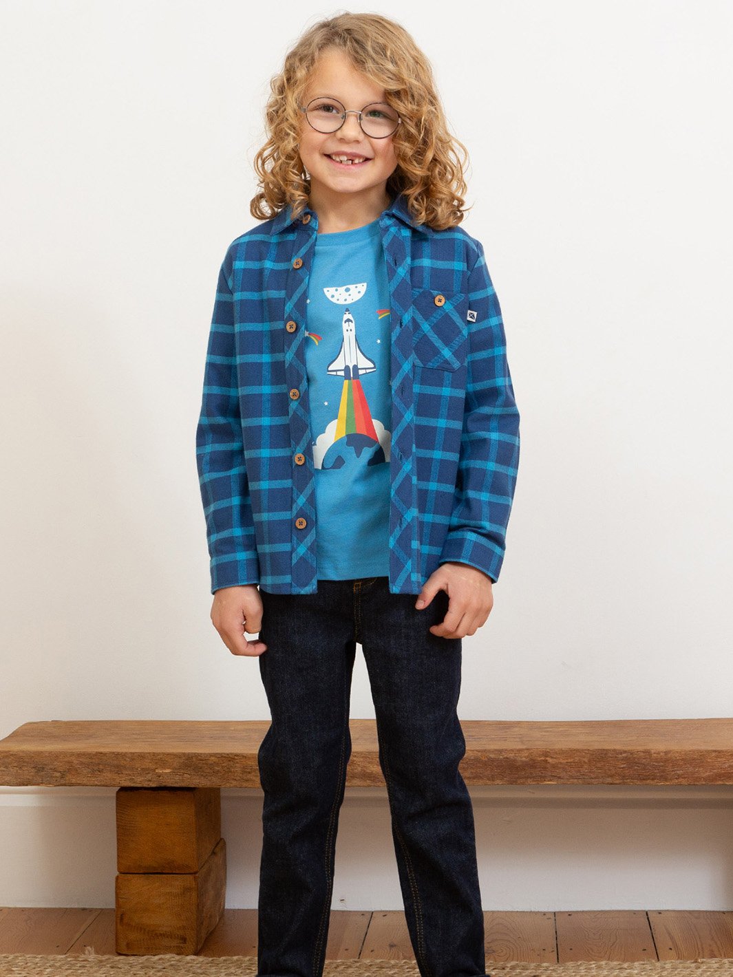Niño vistiendo camisa de franela a cuadros azul marino y calipso, abierta sobre una polera para un look relajado.