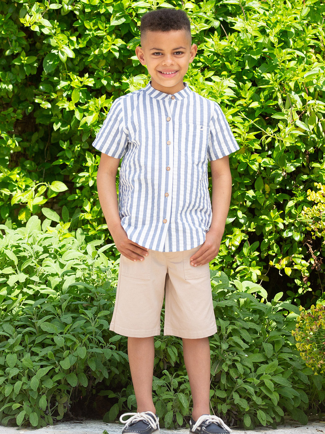 Niño usando la Camisa Clásica de algodón orgánico, combinada con shorts para un look veraniego.