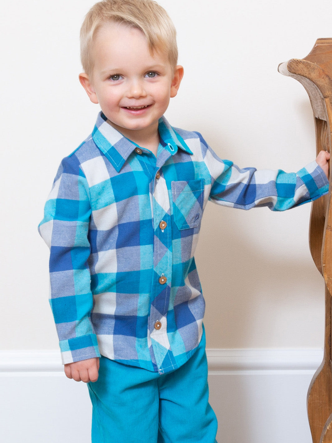 Niño vistiendo la Camisa Cuadros Cool de algodón orgánico en color celeste, look moderno y cómodo para eventos o uso diario.