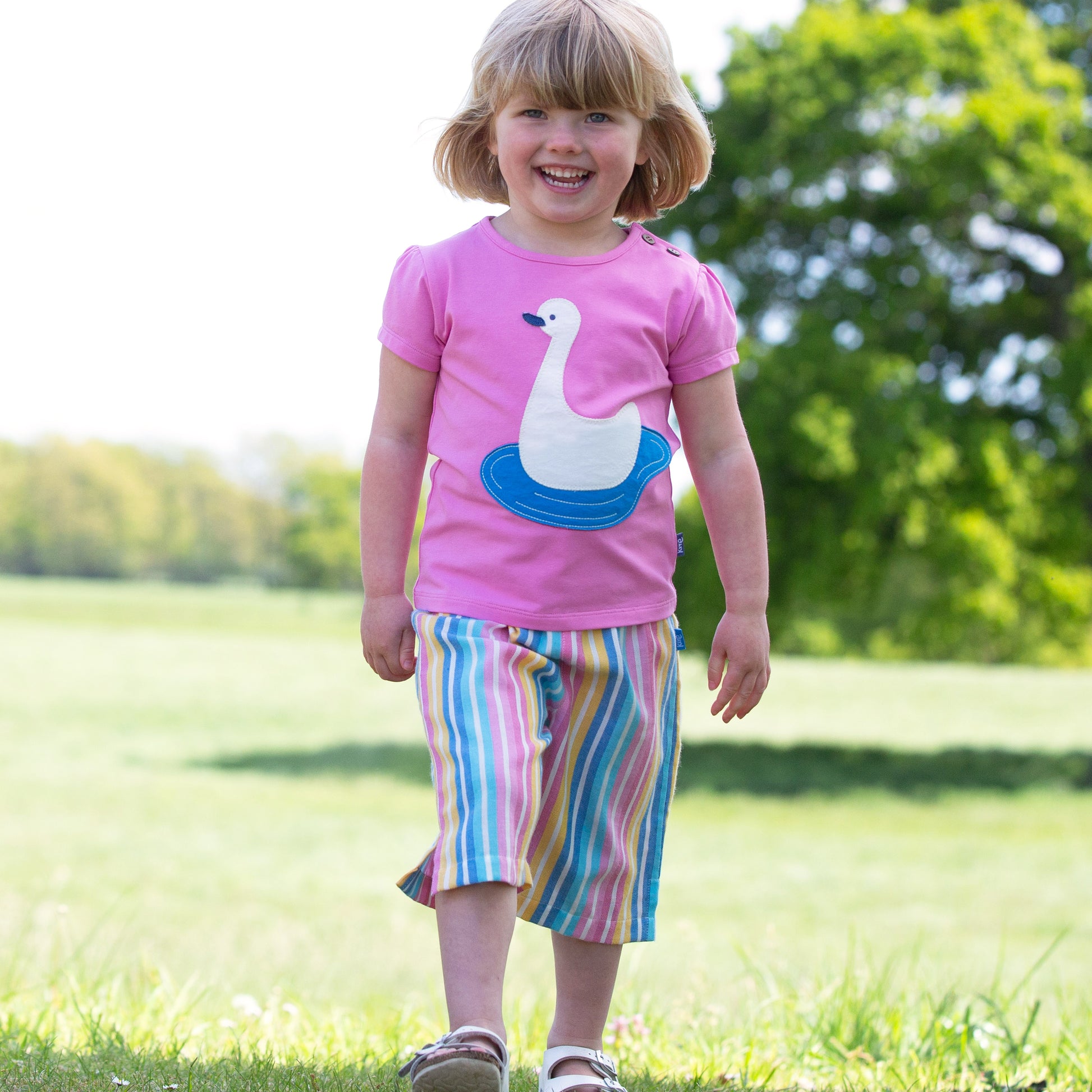 Niña vistiendo el Culotte Rayas Pastel de algodón orgánico, combinado con una polera para un look fresco y relajado.