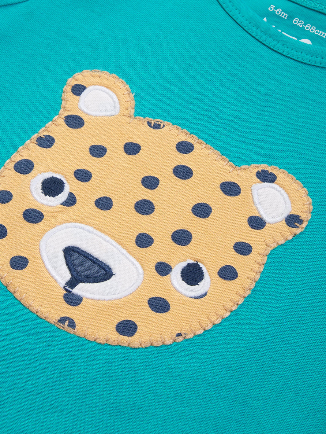 Detalle del apliqué de leopardo cachorro en el Enterito Amigo Leopardo, diseño suave y ecológico.