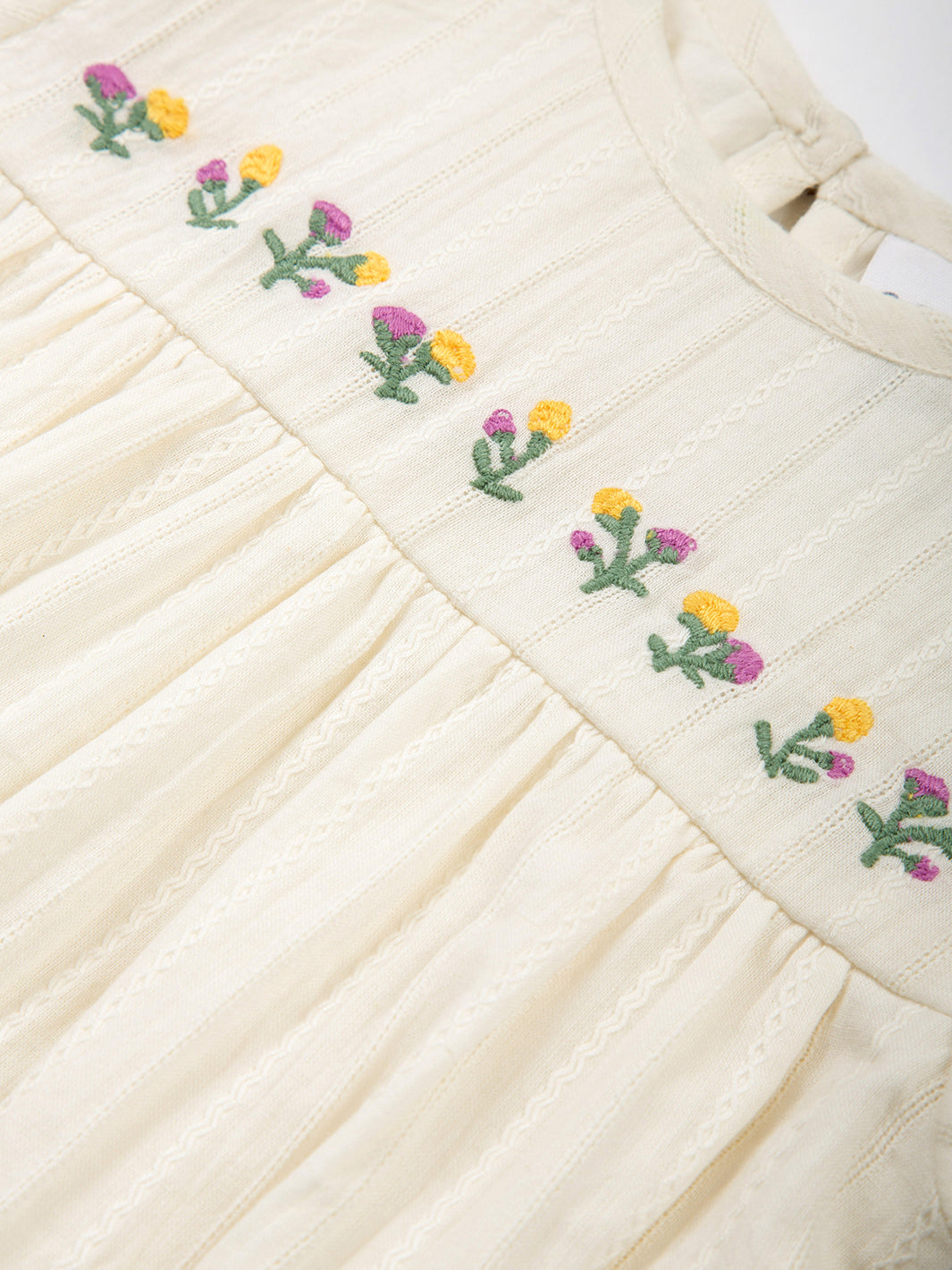 Detalle del bordado de flores en el Enterito Pequeño Brote de algodón orgánico, diseño delicado y elegante.