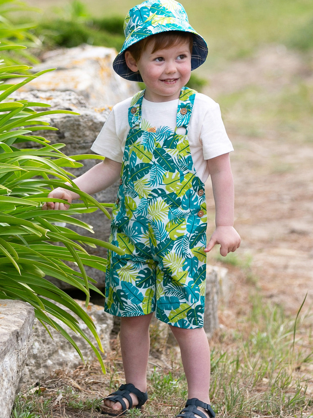 Niño vistiendo la Jardinera Jungla de algodón orgánico, perfecta para días soleados y aventuras al aire libre