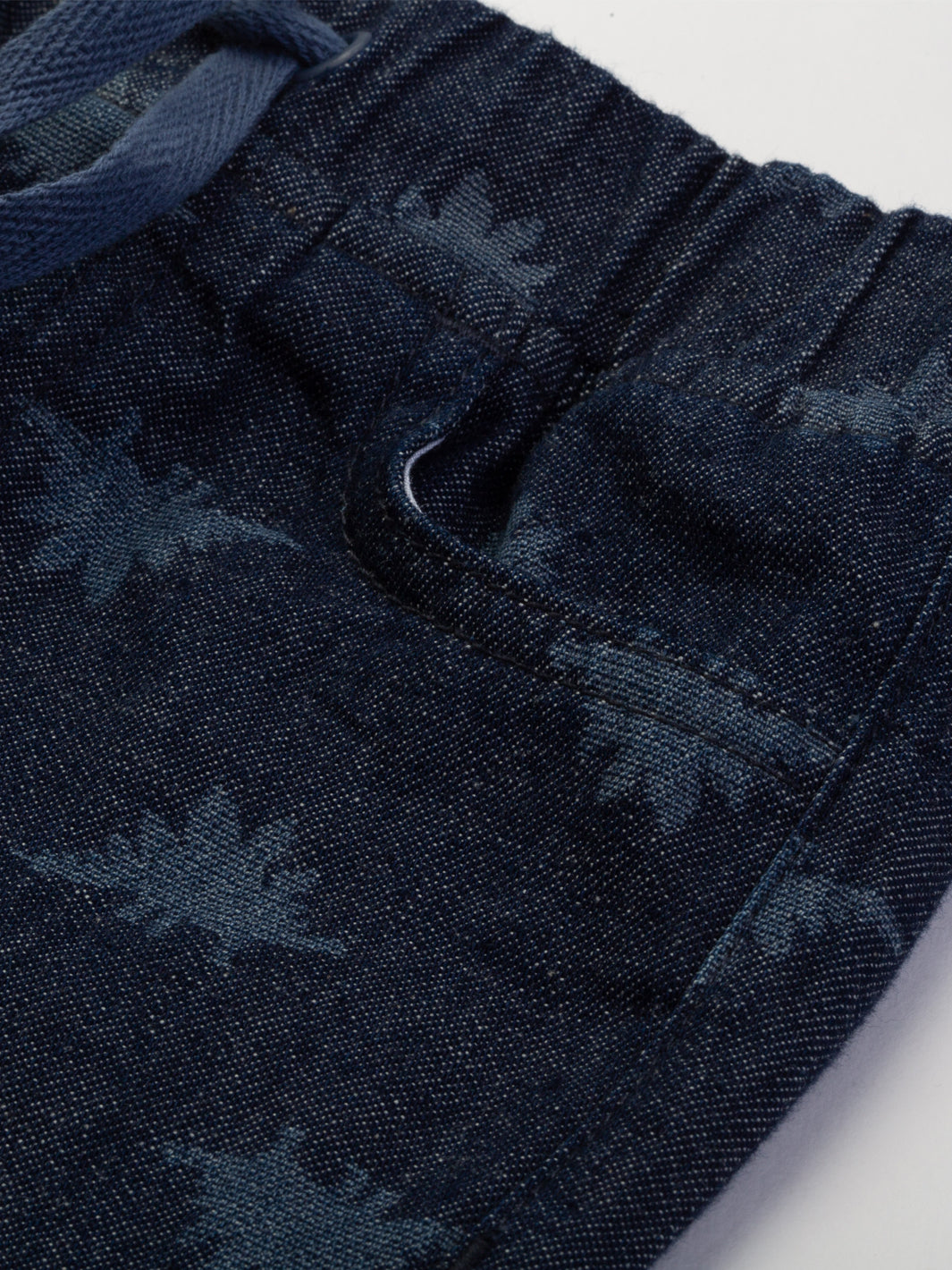 Detalle del estampado láser en jeans de mezclilla liviana, con diseño de Steggie, costuras resistentes y cinturilla elástica con tirantes ajustables