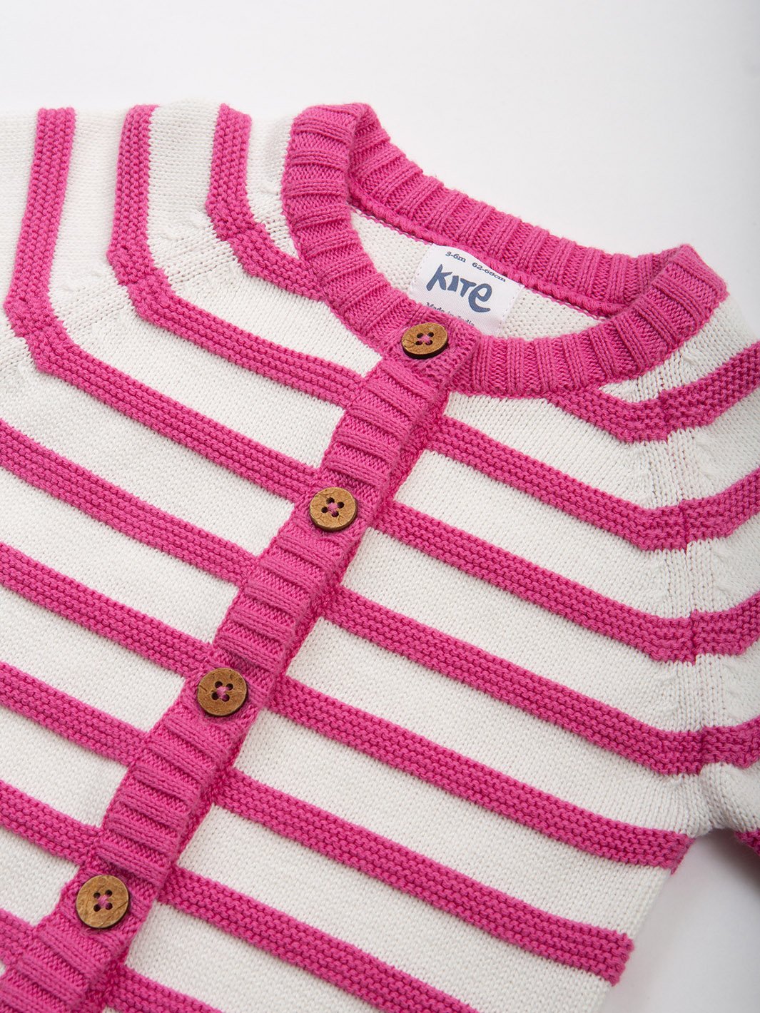Primer plano del chaleco tejido rosa con rayas crema, destacando la textura del punto, el acabado acanalado en puños y cuello, y los botones de coco.