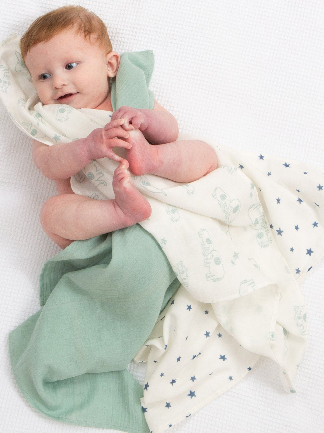 Bebé envuelto en muselinas de algodón orgánico con estampado Ele y Yo, disfrutando de su suavidad y calidez.