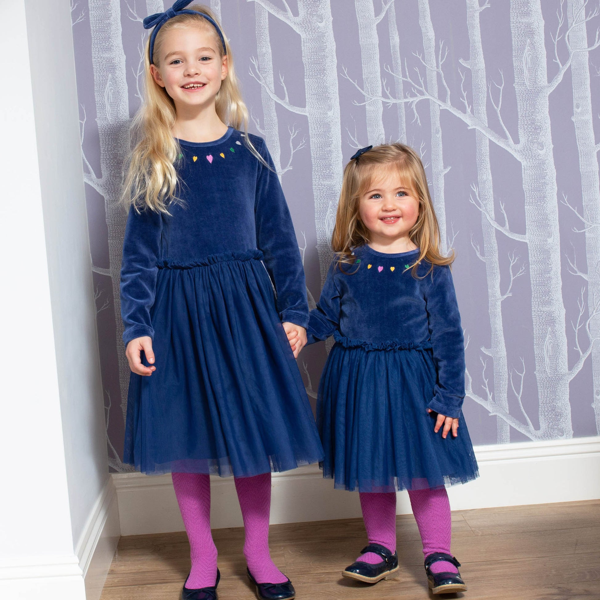 Niñas usando las Pantys de Algodón Orgánico en color orquídea, combinadas con un vestido invernal para un look cálido y cómodo.