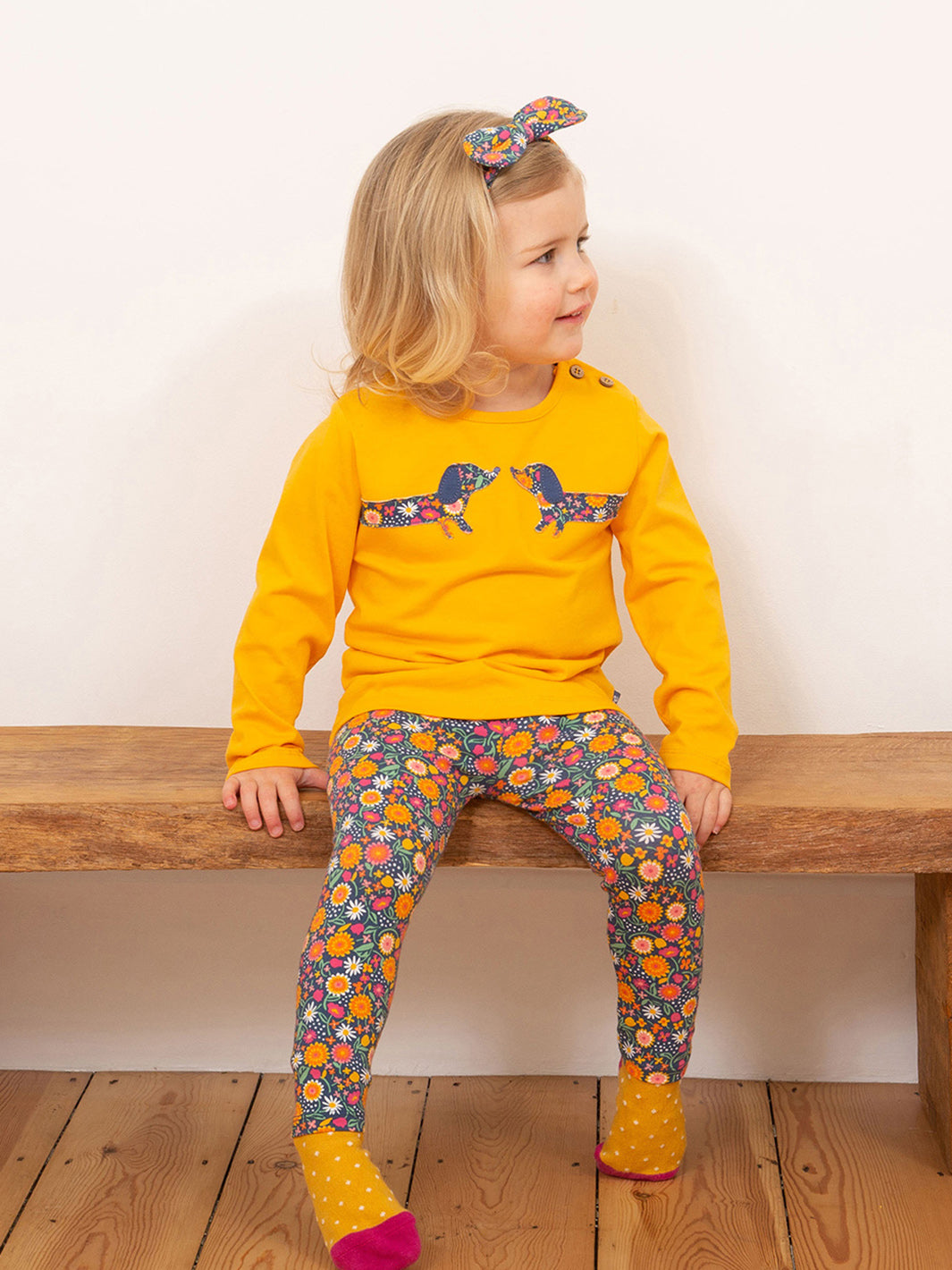 Niña usando la Polera Amigos Salchichas de algodón orgánico, combinada con calzas para un look cómodo y divertido.