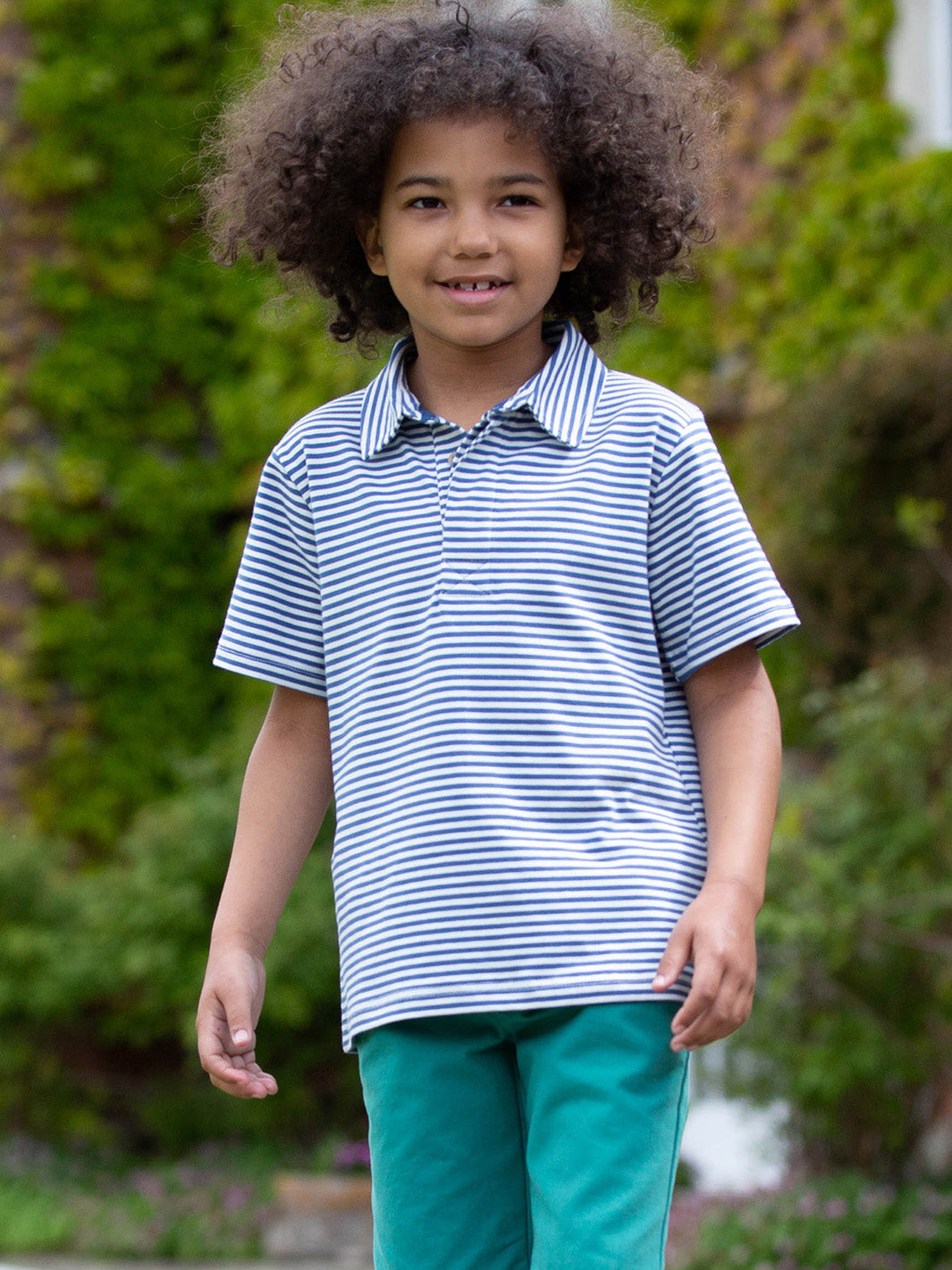 Niño usando la Polera Cuello Polo de algodón orgánico, combinada con pantalón para un look casual y elegante.