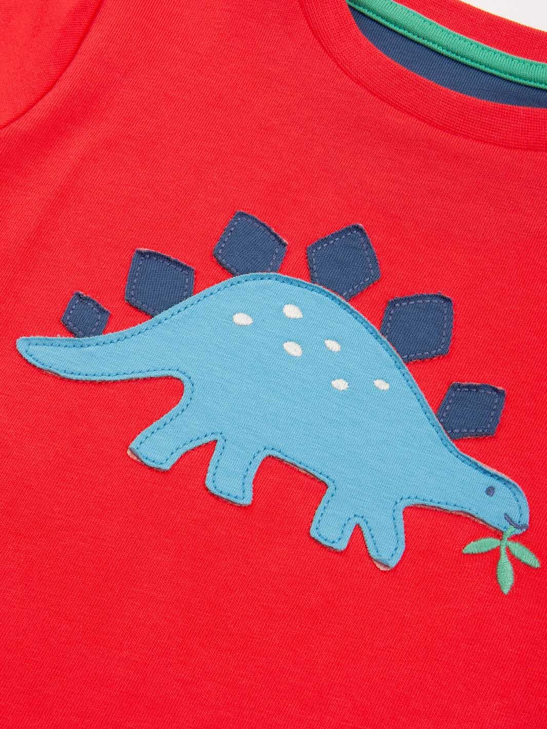 Detalle del aplique de dinosaurio azul en polera roja de algodón orgánico para niño.