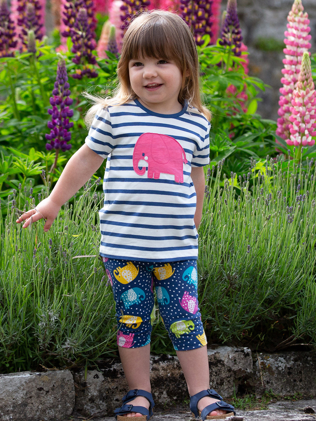 Niña vistiendo la Polera Ele Dot de algodón orgánico, combinada con calzas cortas para un look cómodo y moderno.