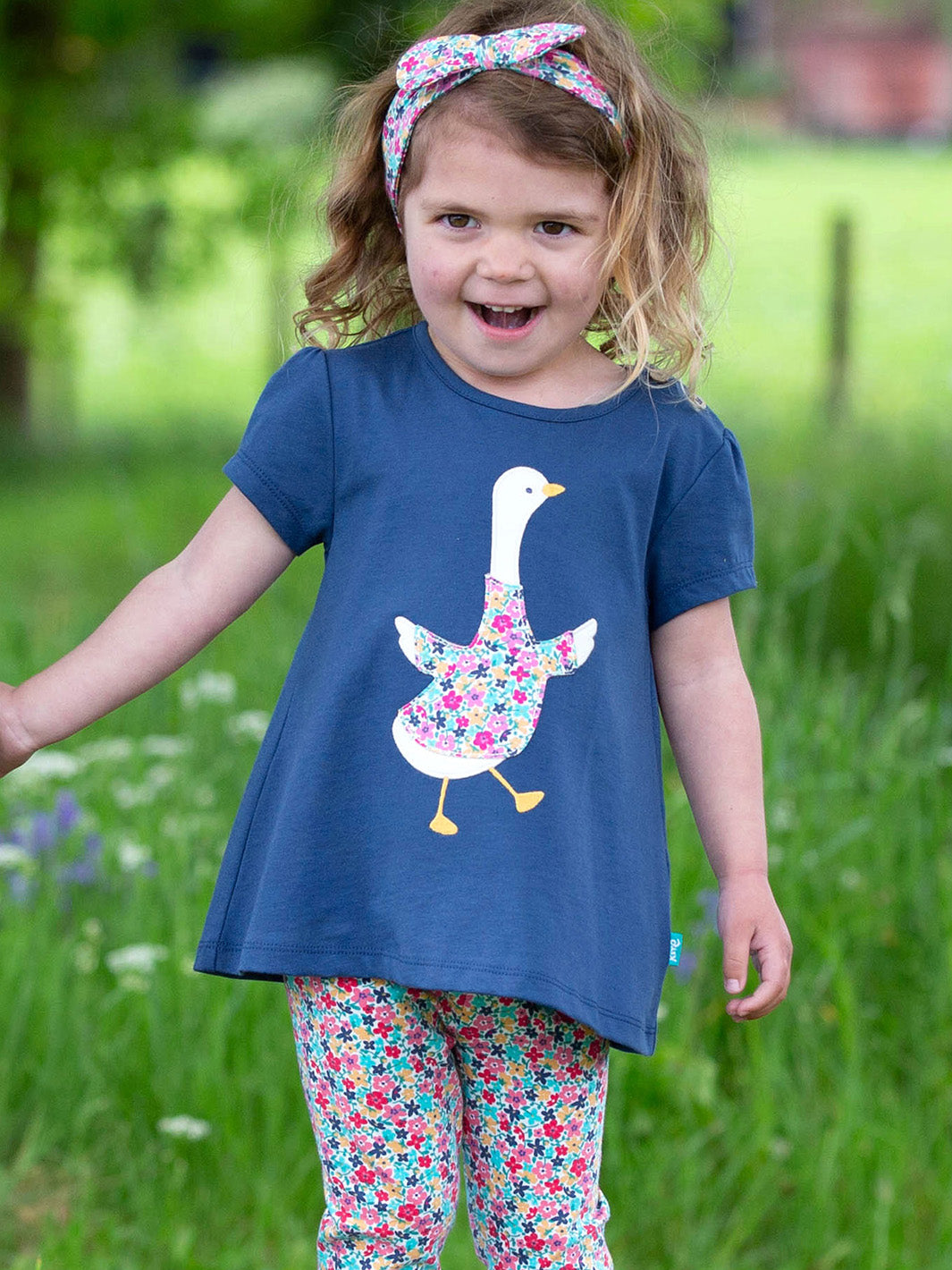 Niña usando la Polera Gansito Floral de algodón orgánico, combinada con calzas para un look fresco y adorable.