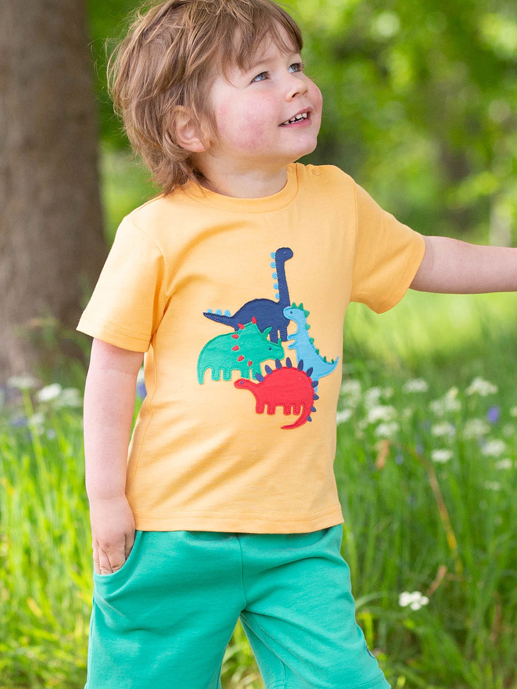 Niño usando la Polera Juego de Dinosaurios de algodón orgánico, combinada con shorts para un look fresco y aventurero.