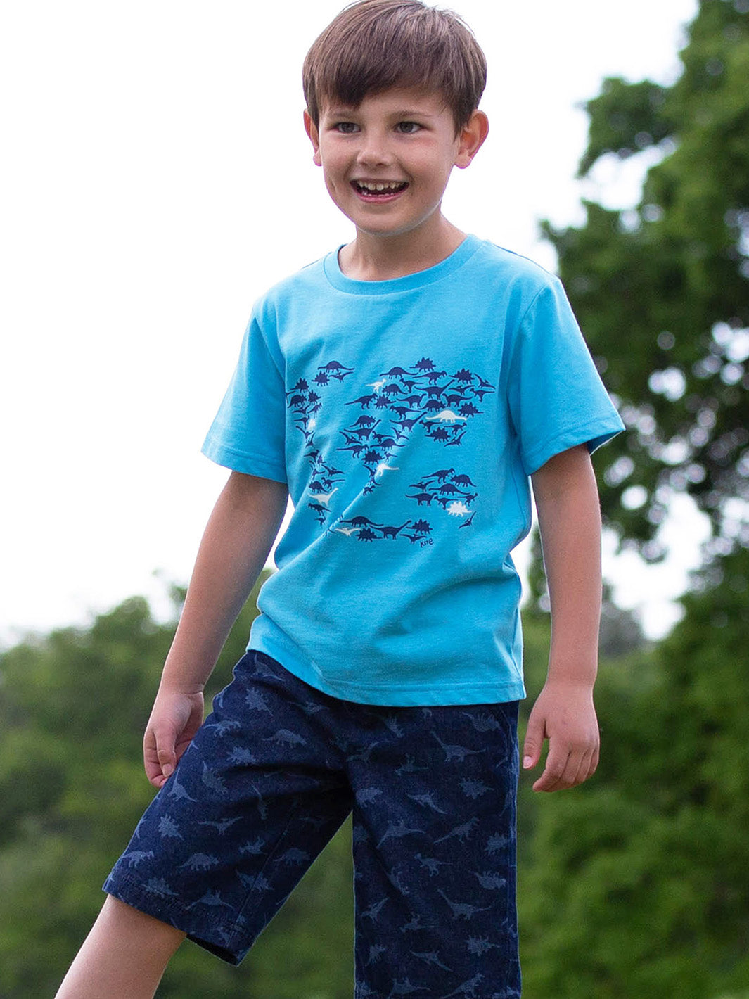 Niño vistiendo la Polera Mundo Dinosaurio con shorts de algodón orgánico, look ideal para pequeños exploradores.
