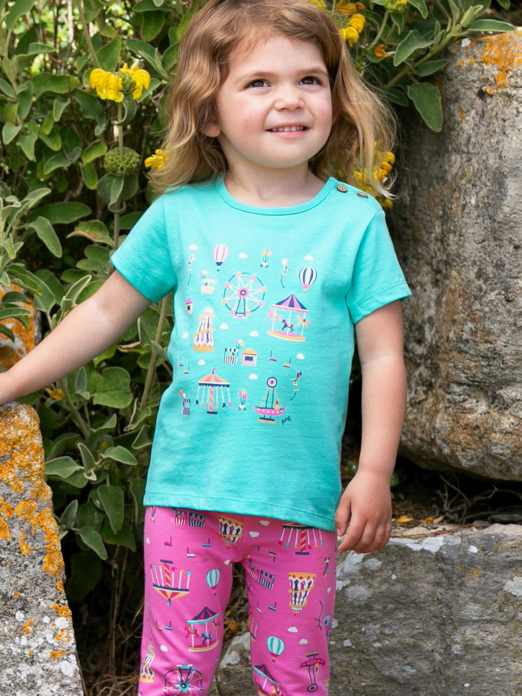 Niña usando la Polera Parque de Diversiones de algodón orgánico, combinada con faldas pantalón para un look fresco y alegre.