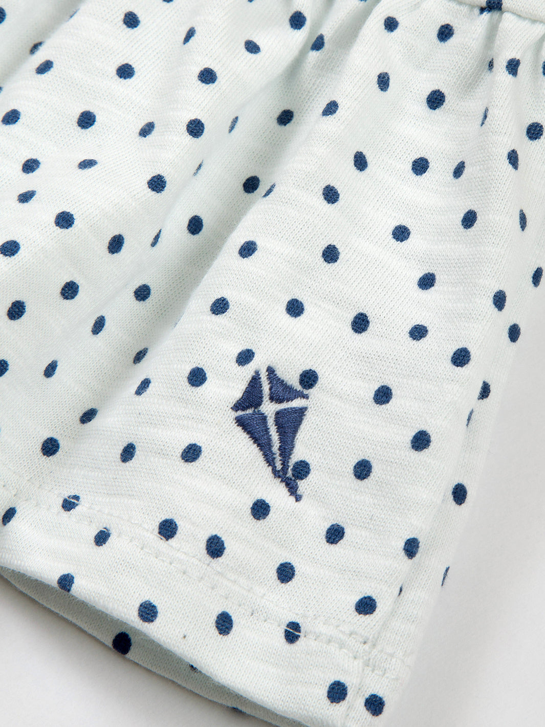 Detalle del dobladillo con volantes en la Polera Pequeños Lunares de algodón orgánico, diseño femenino y cómodo.