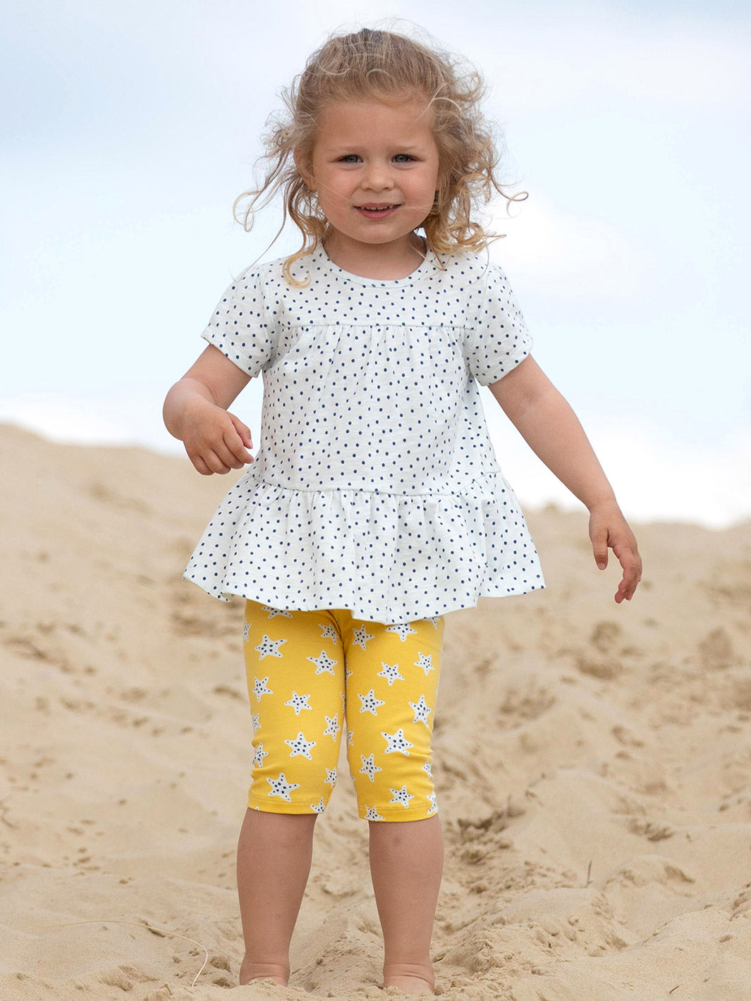Niña usando la Polera Pequeños Lunares de algodón orgánico, combinada con una falda para un look fresco y adorable.