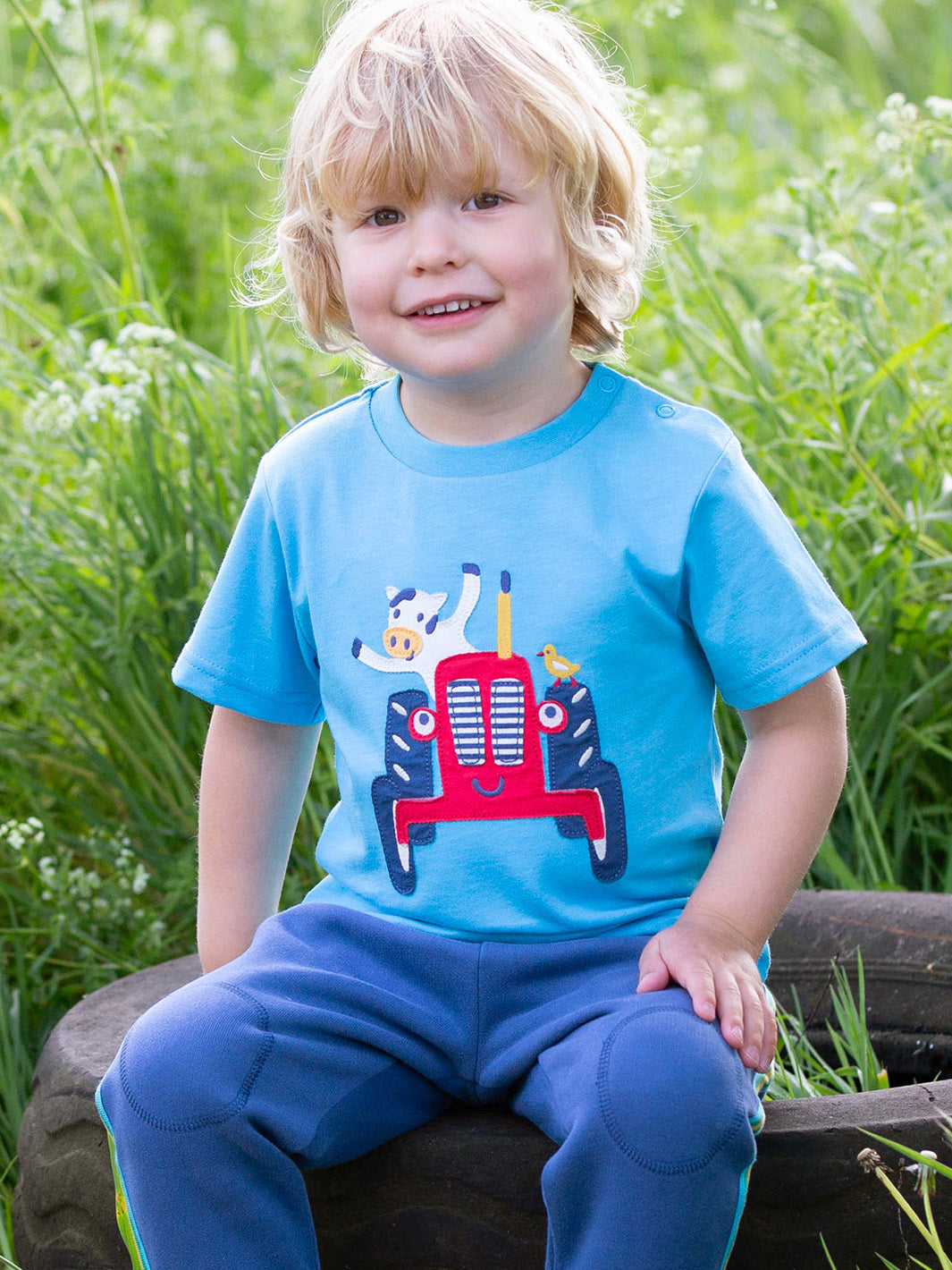 Niño usando la Polera Vaca Tractorista de algodón orgánico, combinada con pantalón para un look campestre y cómodo.