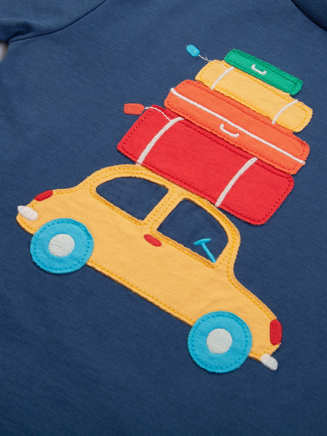 Detalle del aplique de automóviles en la Polera Vacaciones de algodón orgánico, diseño divertido y ecológico.