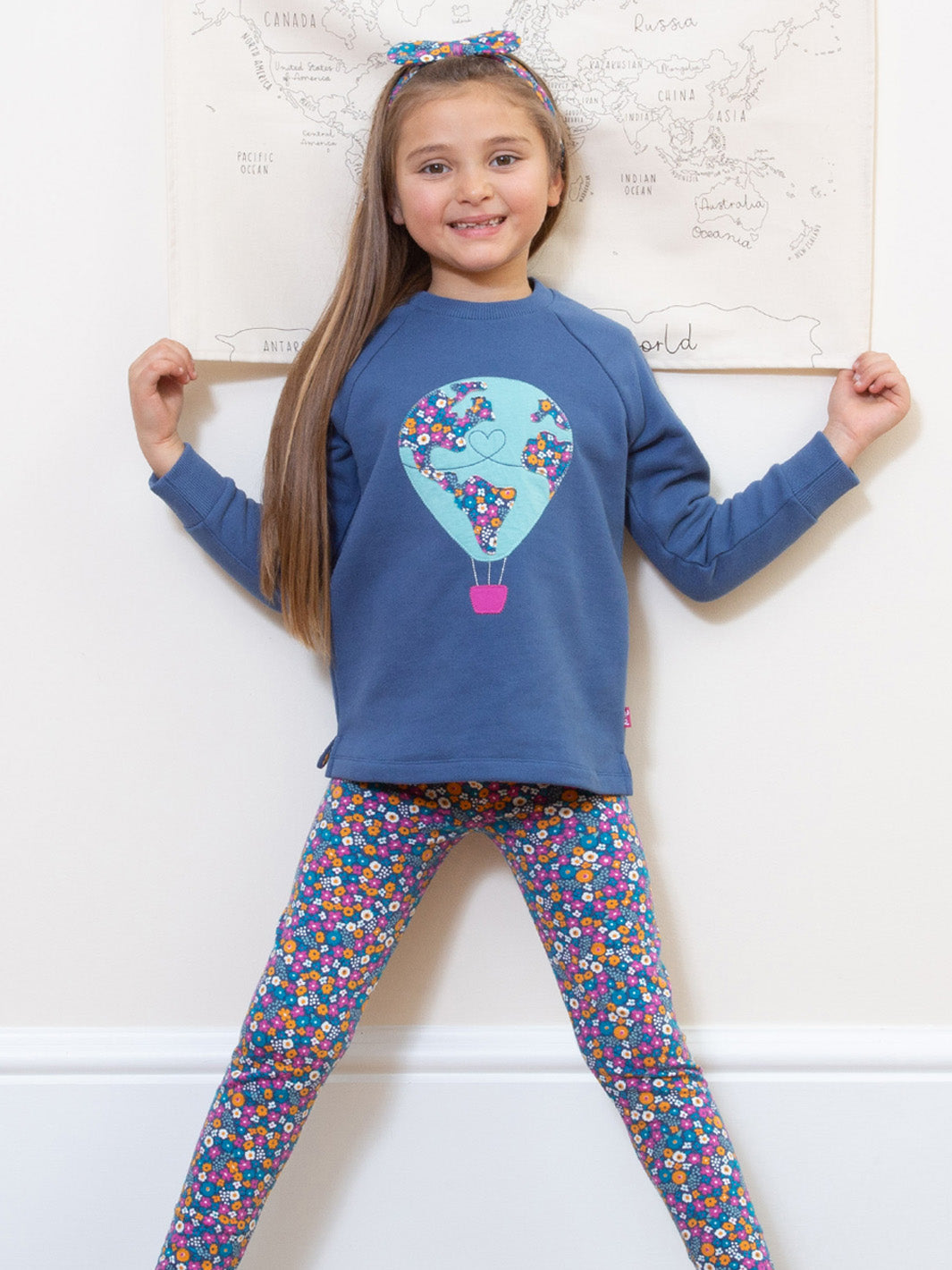 Niña usando el Polerón Planeta Globo de algodón orgánico, combinado con calzas para un look cálido y aventurero.