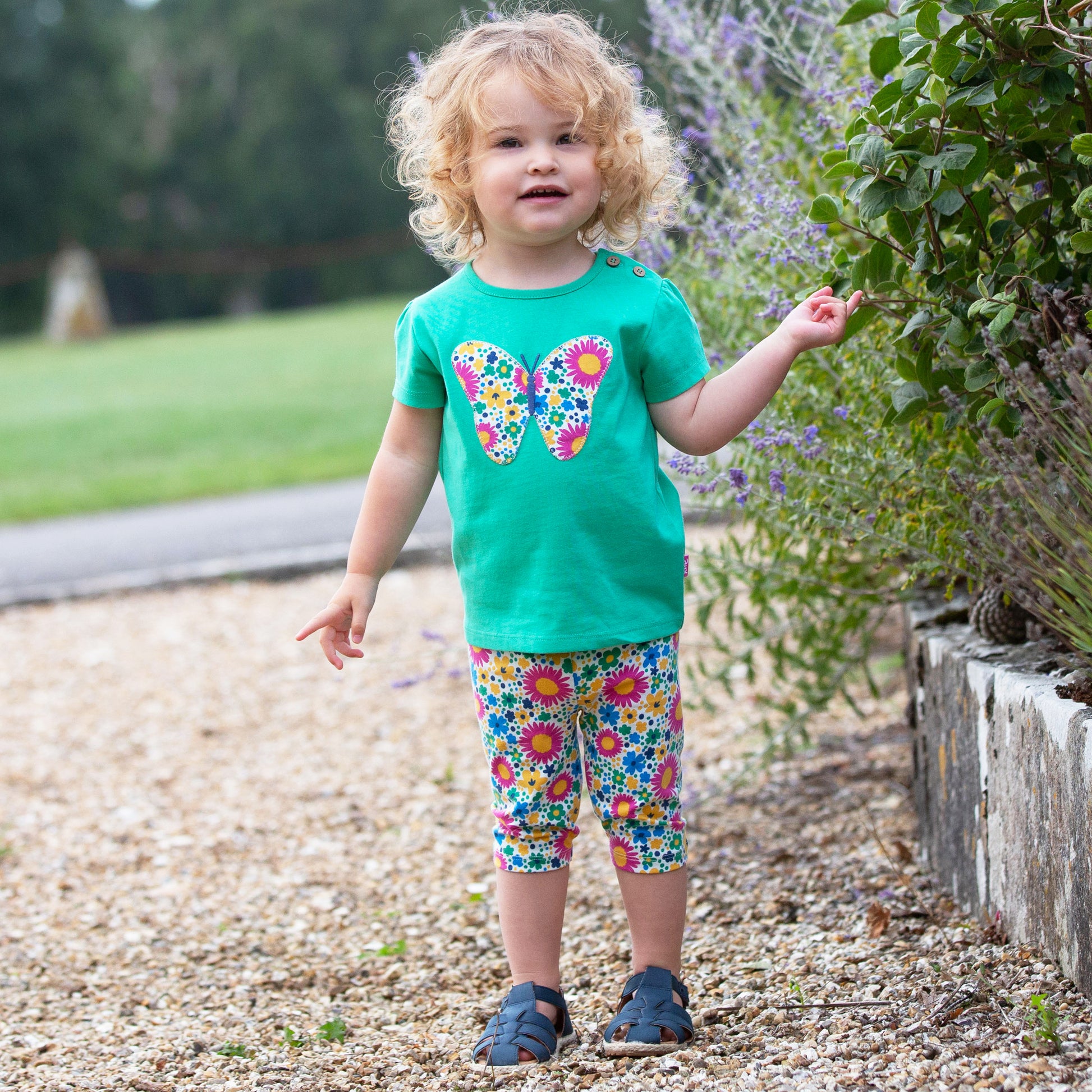 Niña vistiendo calzas 3/4 de algodón orgánico con estampado de flores grandes, combinadas con una polera para un estilo alegre y moderno.