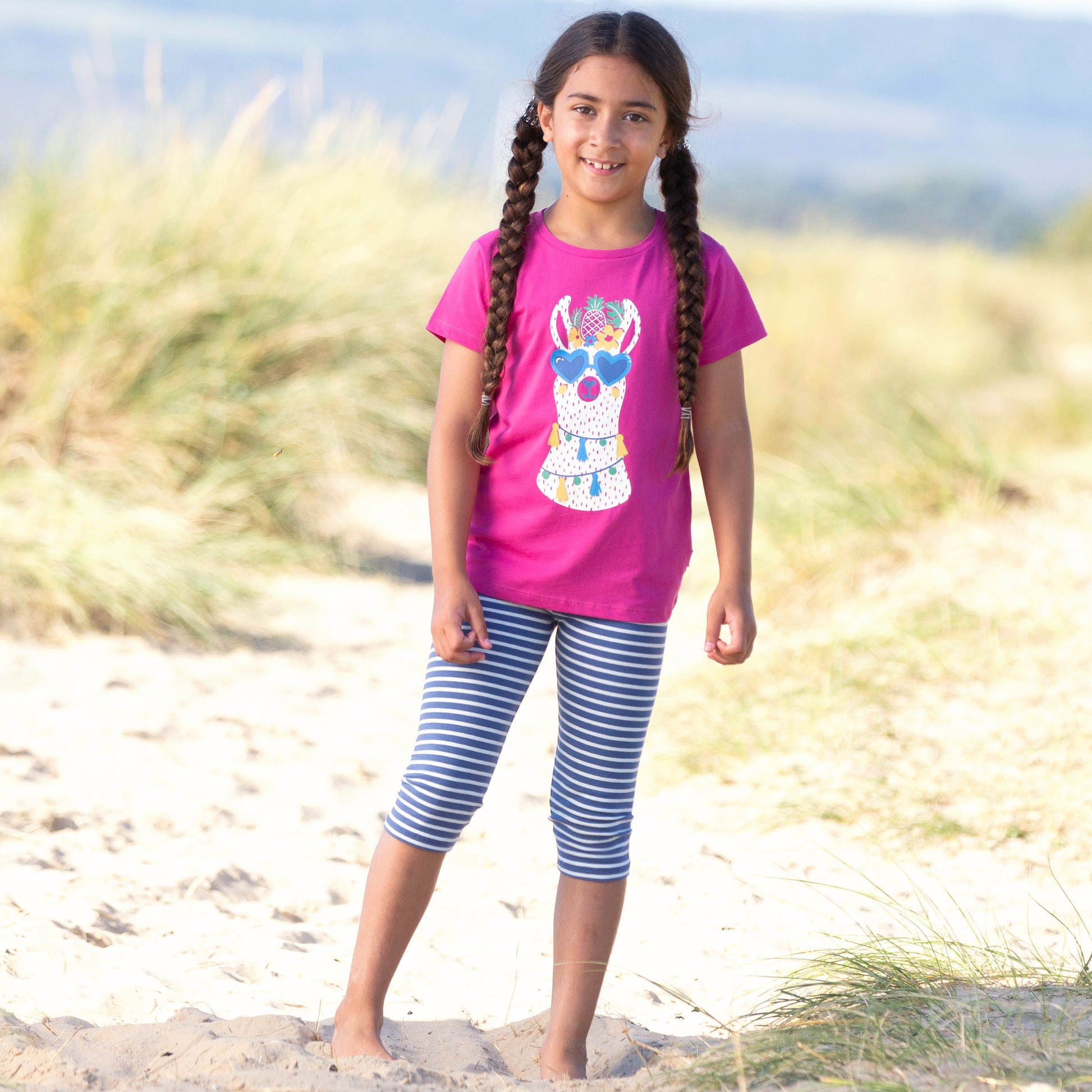 Niña vistiendo calzas 3/4, de algodón orgánico con rayas azul y blanco estilo marinero, combinadas con una polera para un look náutico y versátil