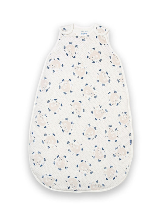 Saco de dormir de algodón orgánico color crema con estampado de osito abrazable, cierre bidireccional y broches en los hombros.