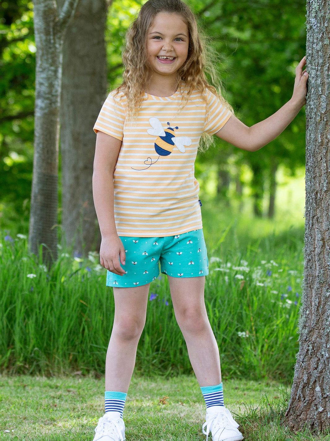 Niña vistiendo short verde menta con estampado de abejas reinas, combinándolo con una polera para un look fresco y cómodo.