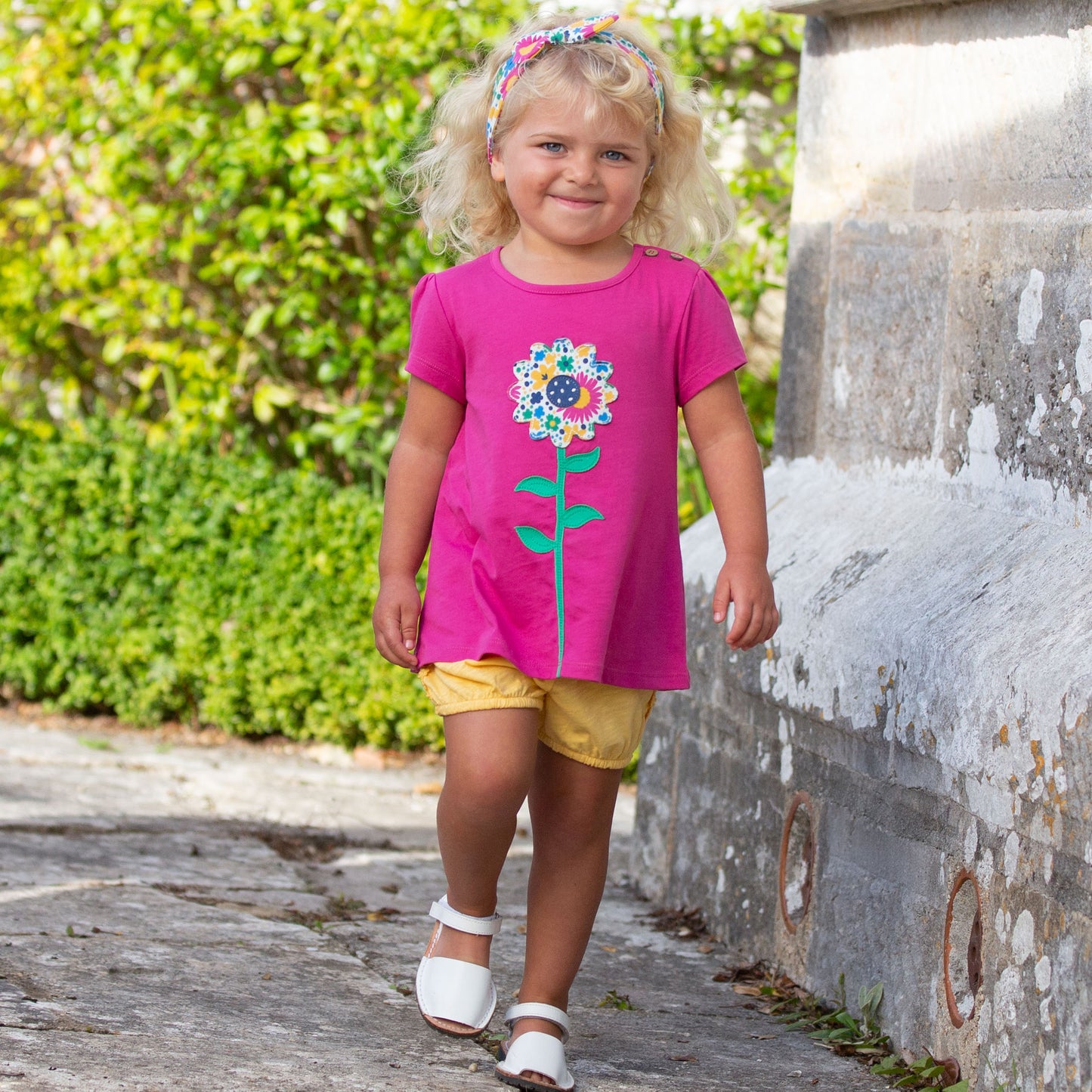 Niña usando el Short Burbuja amarillo de algodón orgánico, combinado con una polera para un look fresco y veraniego.