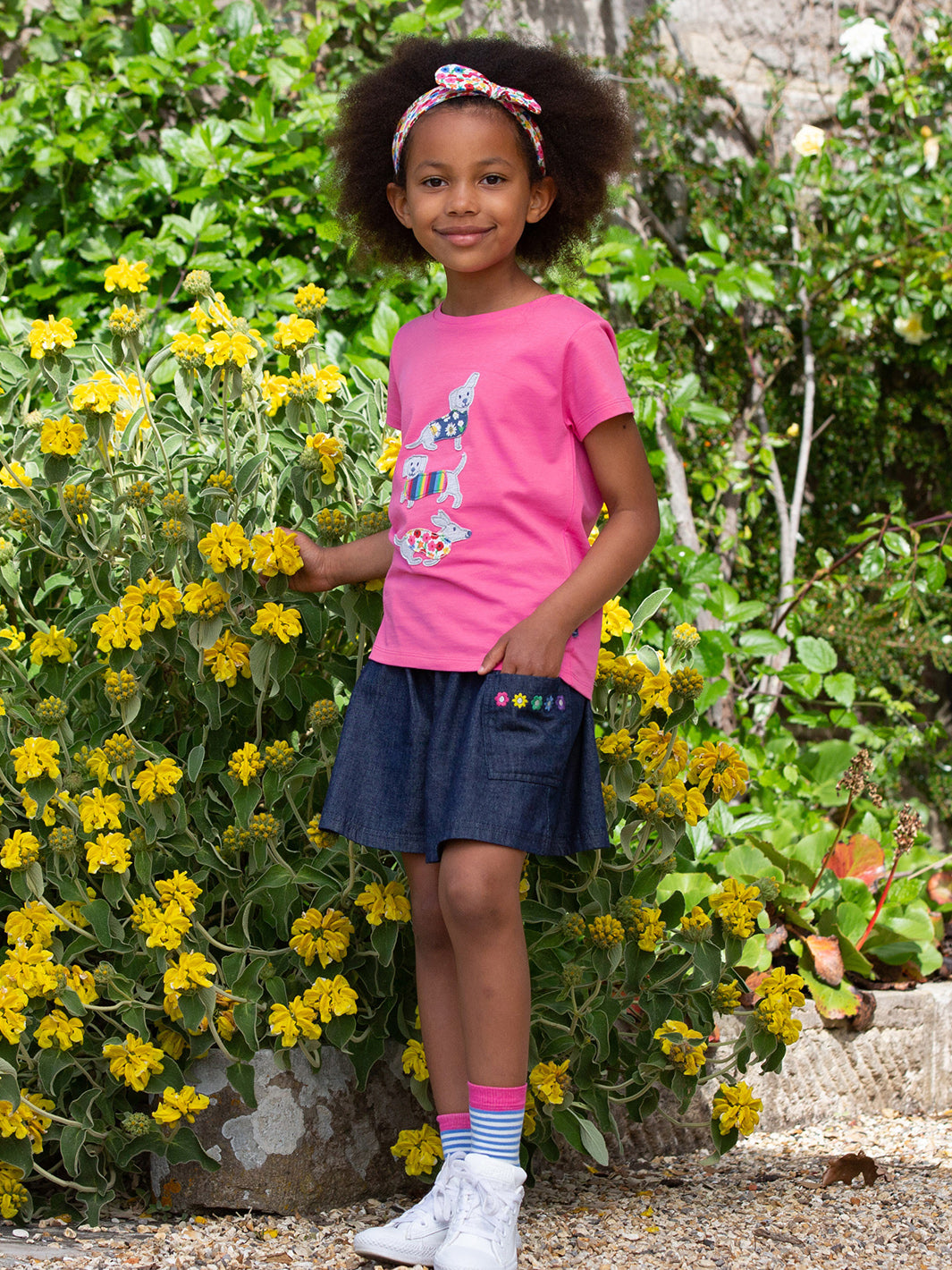 Niña vistiendo el Short Margarita de mezclilla azul marino con bordado de margaritas, combinado con una polera de algodón orgánico.