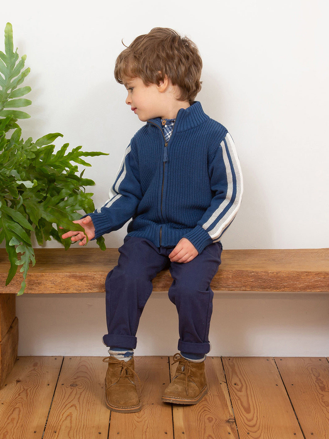 Niño vistiendo el Sweater Punto Grueso de algodón orgánico, combinado con pantalones para un look abrigado y elegante.