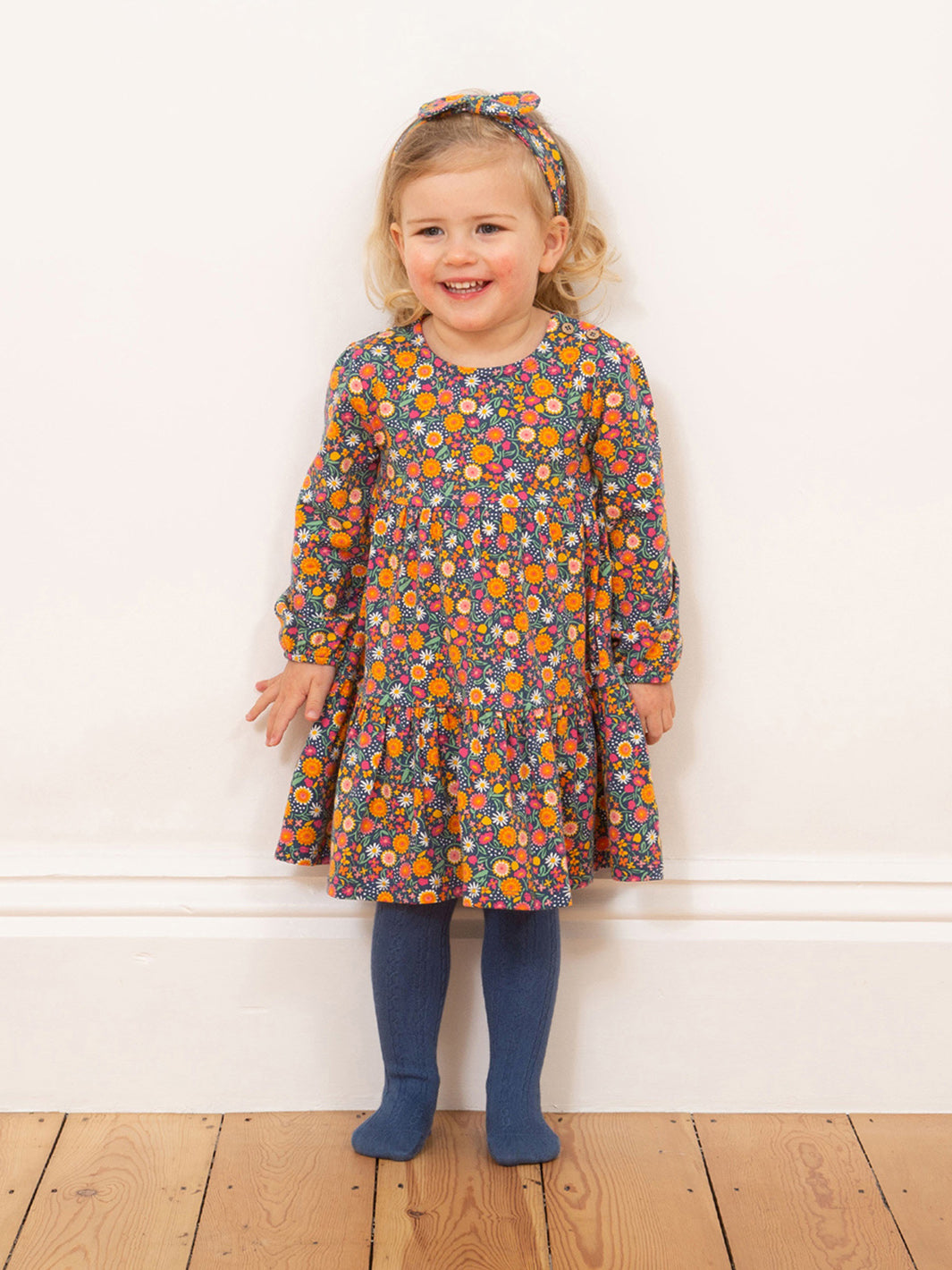 Niña usando el Vestido Flores de Amor de algodón orgánico, con pantys y cintillo, un look dulce y cómodo.