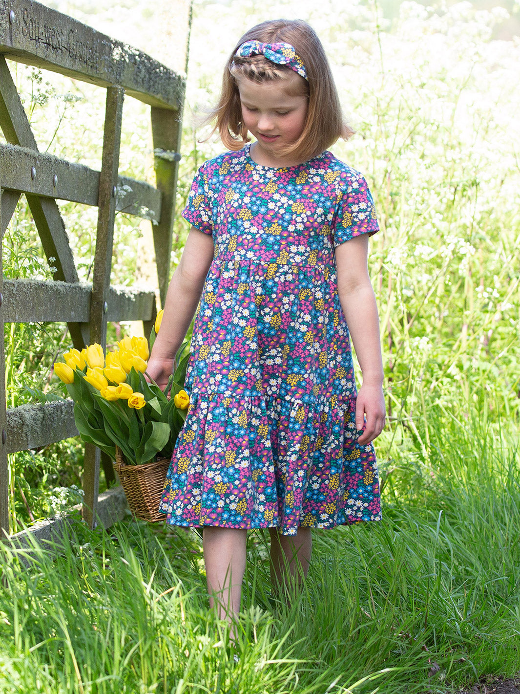 Niña usando el Vestido Jardín de Flores de algodón orgánico, con falda fluida y diseño encantador.