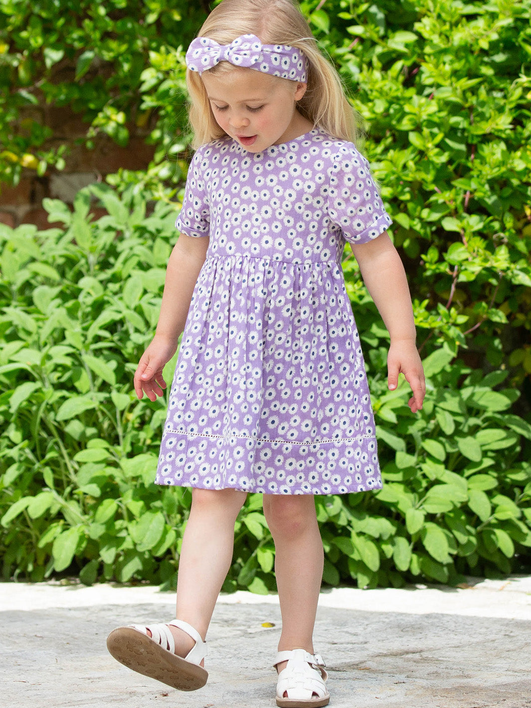 Niña usando el Vestido Lavanda de algodón orgánico, combinado con el cintillo lavanda para un look encantador.