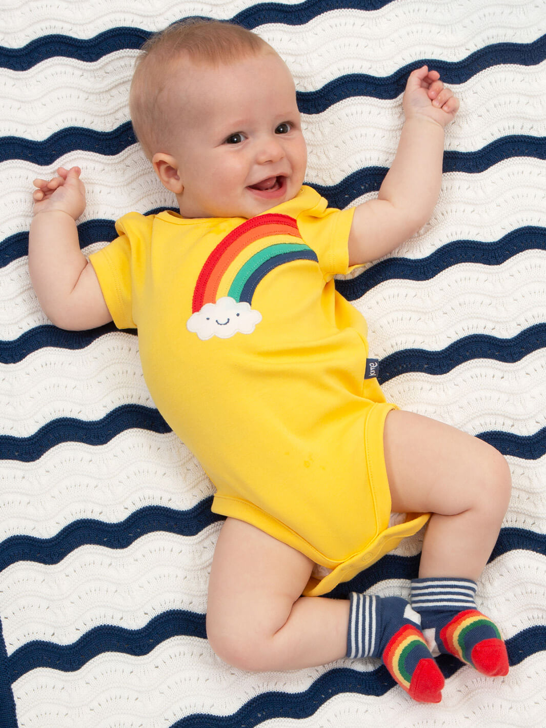 Guagua usando body arcoíris feliz en algodón orgánico, ropa infantil sustentable Chile.