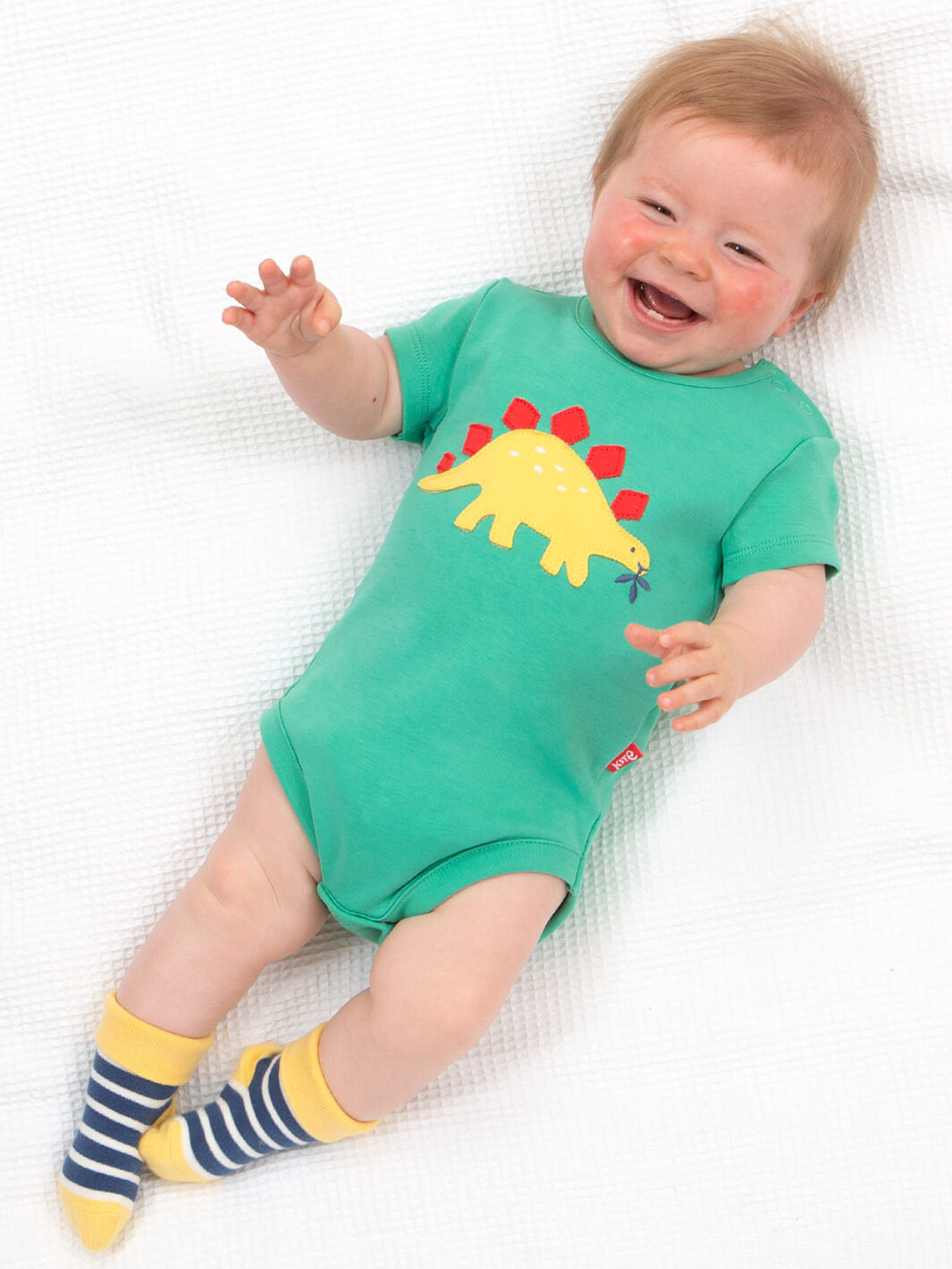 Guagua usando body día de dinosaurios en algodón orgánico, ropa infantil sustentable Chile.