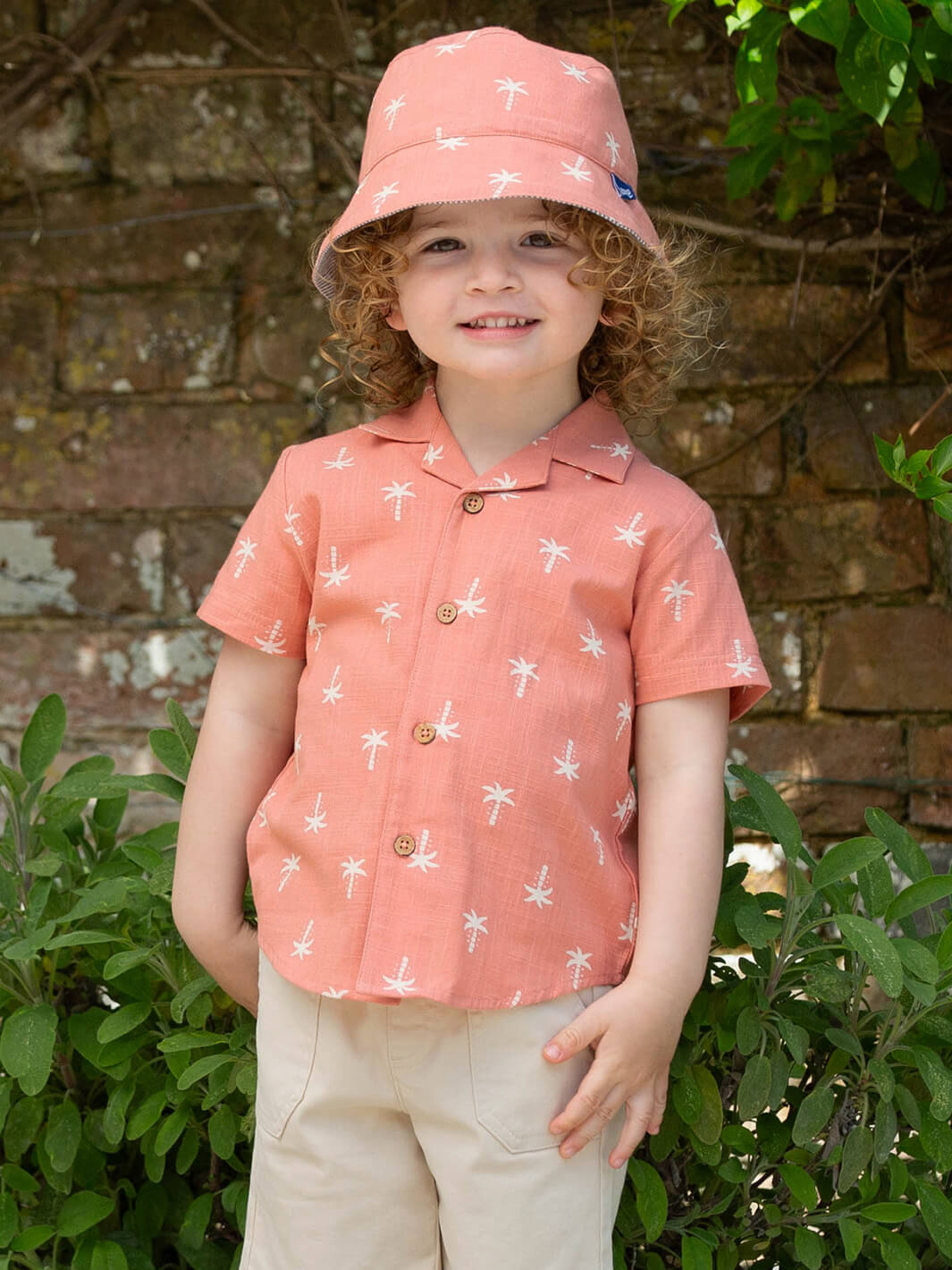 Niño usando camisa de algodón orgánico terracota con estampado de palmeras