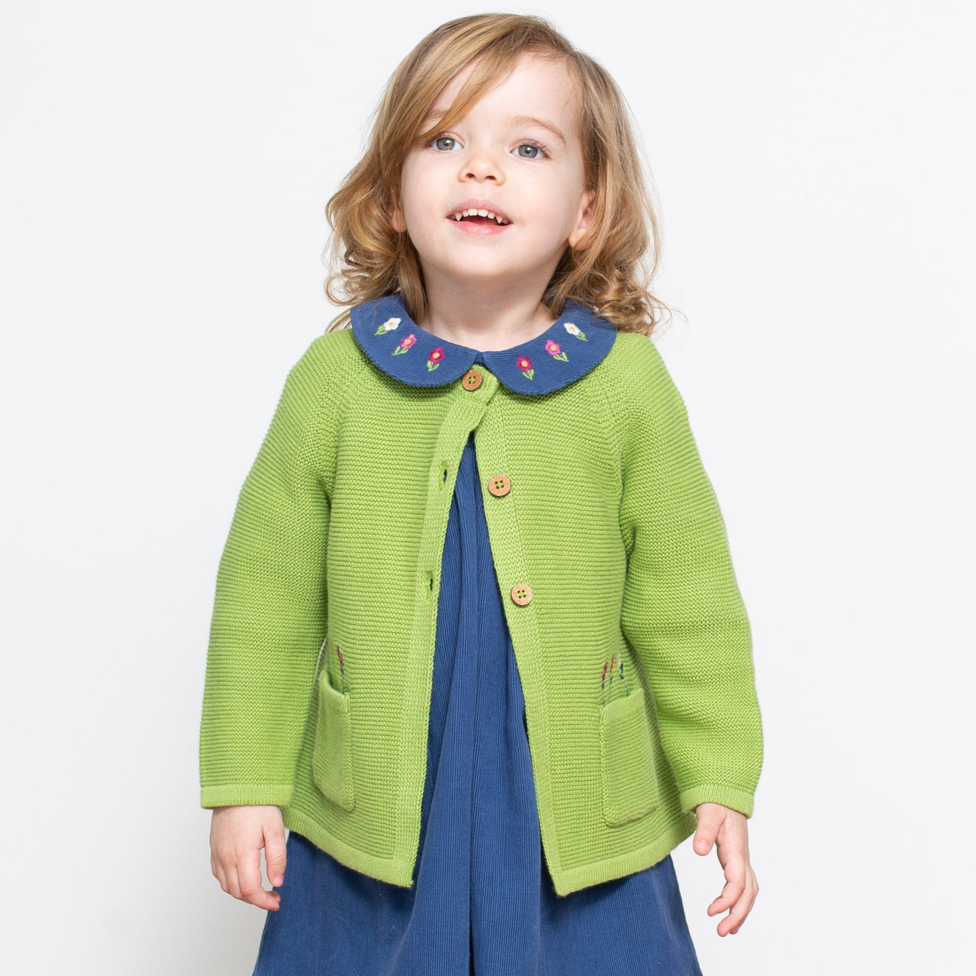 Niña con el Chaleco Floral de algodón orgánico sobre un vestido, combinación elegante y versátil para cualquier ocasión.