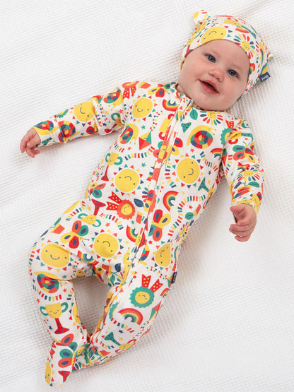 Bebé usando enterito de algodón orgánico con estampado alegre de soles, arcoíris y figuras coloridas.