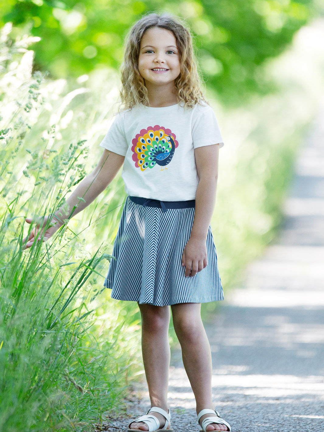 Niña usando la falda patinadora de algodón orgánico, con cinturilla elástica, lazos ajustables y diseño a rayas.
